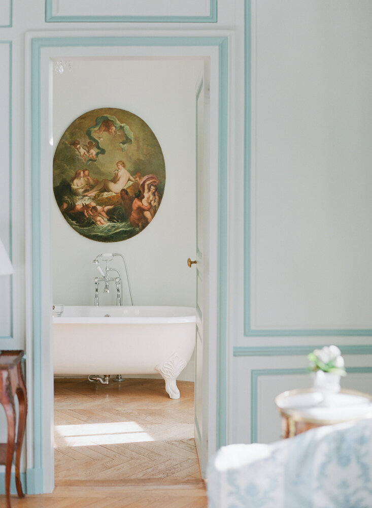 Light blue bedroom with dark blue trim, claw footed rolltop bathtub in next room