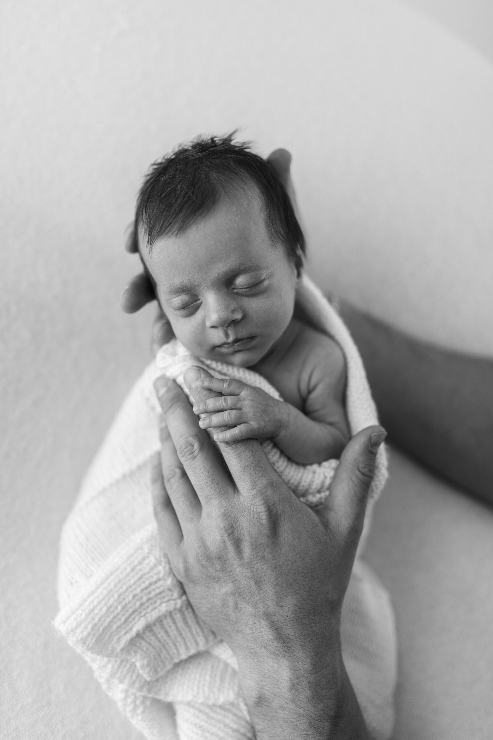 Baby in dads hands black and white photograph 