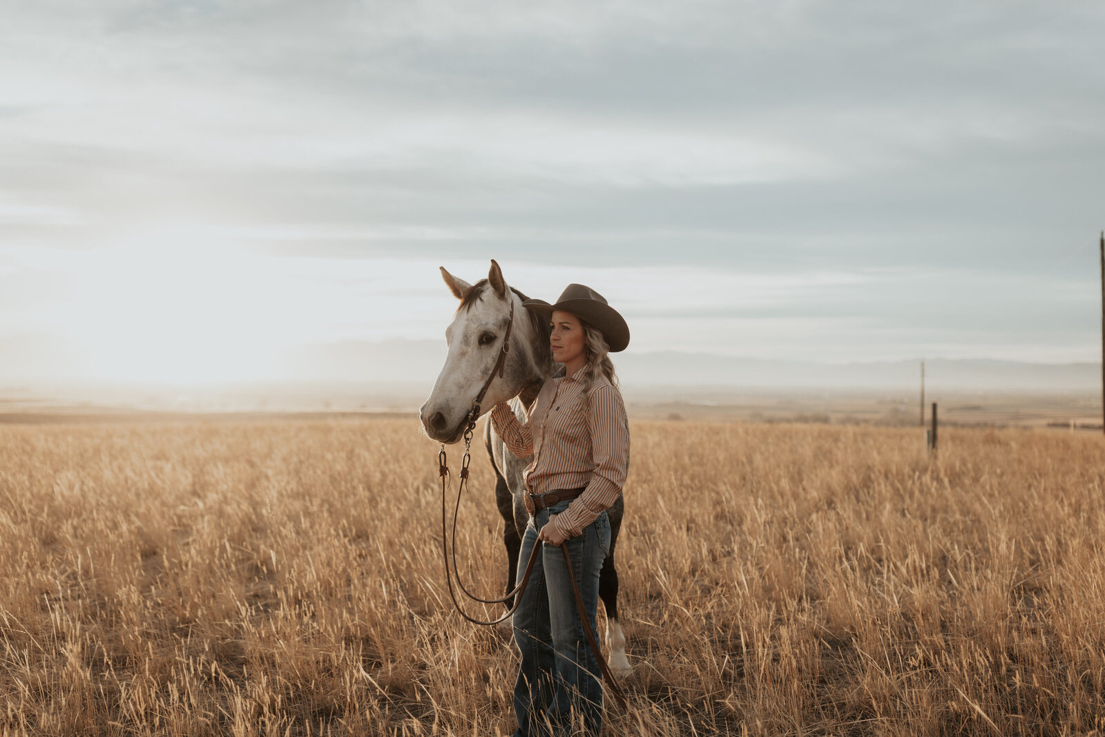 Cowgirl watches the horizon with her horse