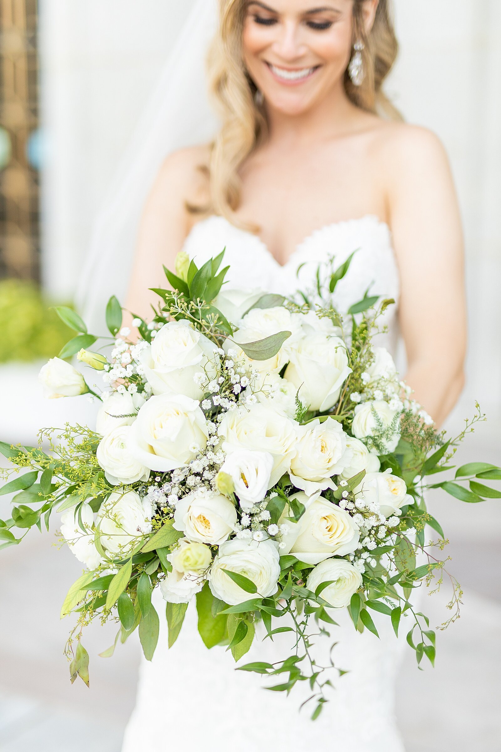 Bride holding large white bridal bouquet.