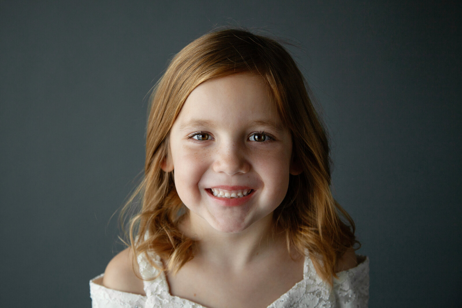 Girl smiling at camera gray background.