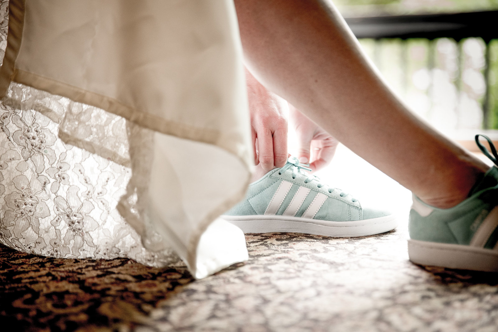Bride ties the shoelace of her sneaker as she dresses for her wedding