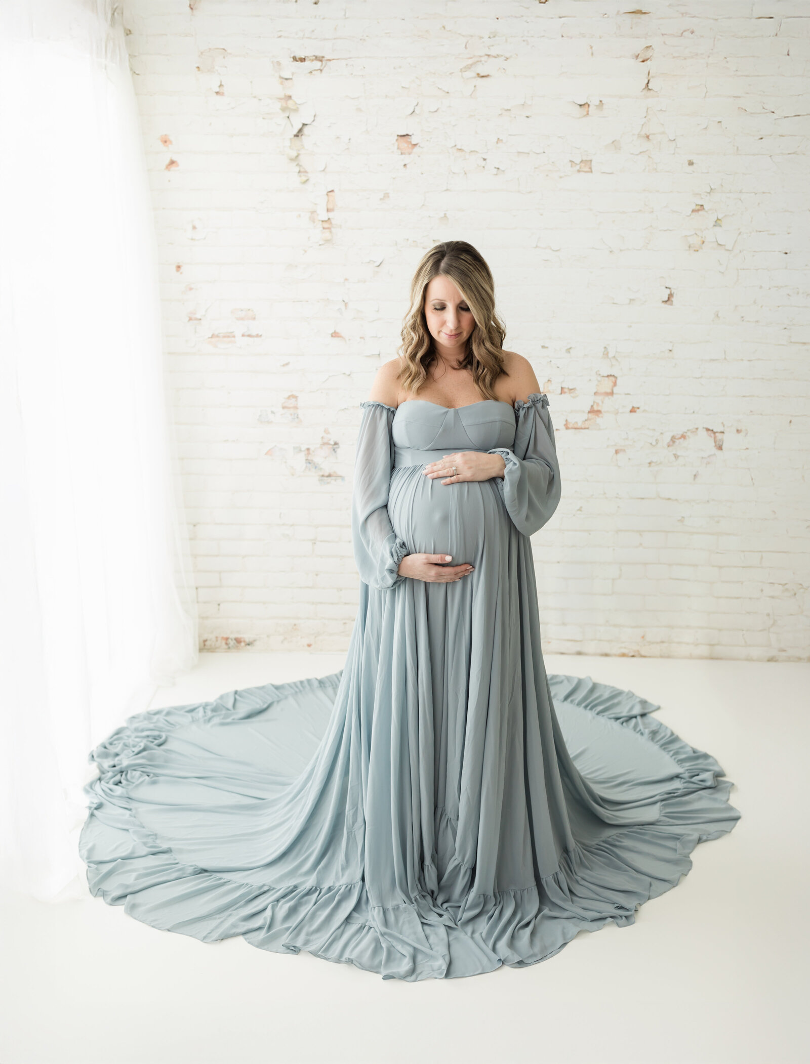 pregnant mother in blue maternity gown holding baby bump for maternity photoshoot