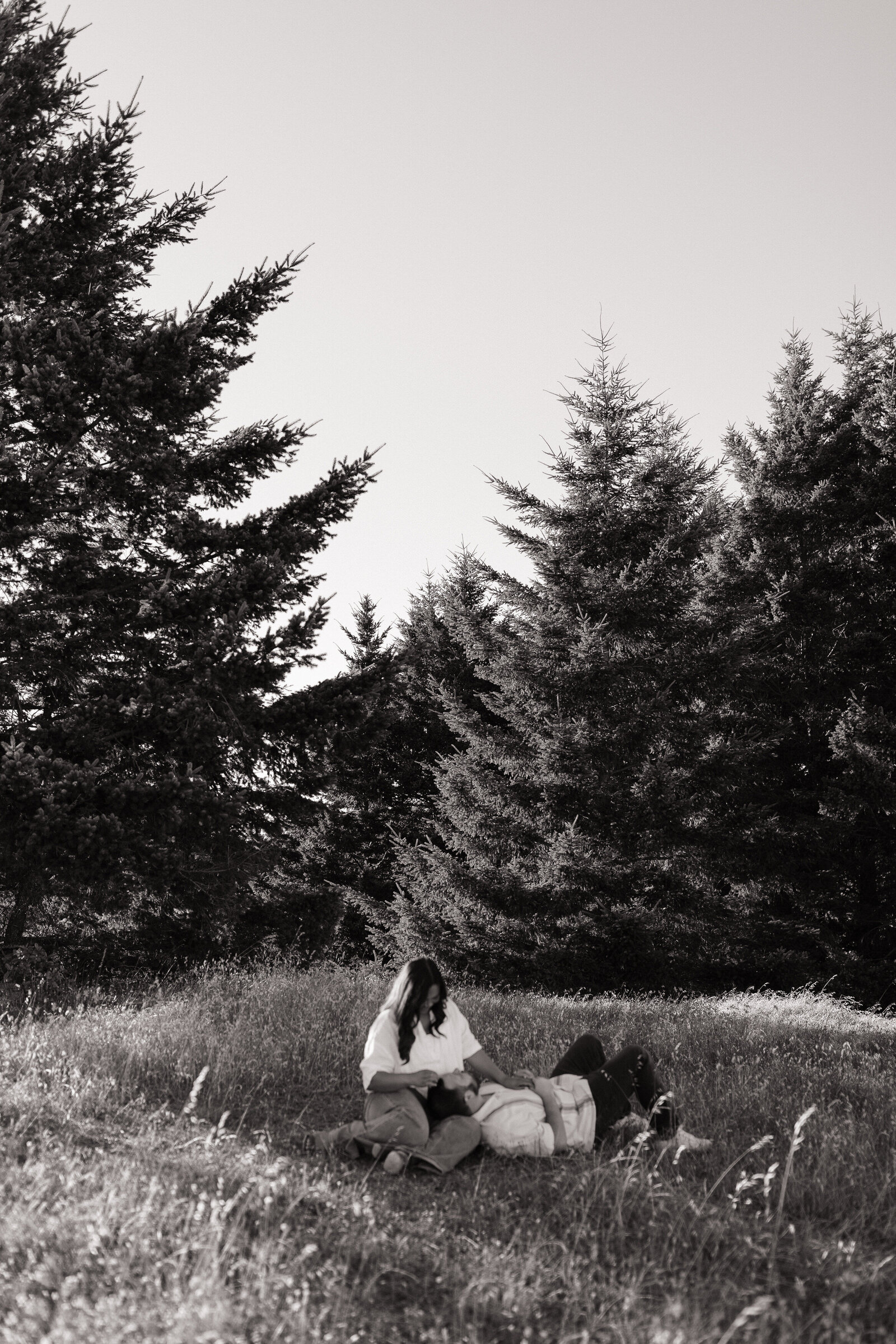 Romantic engagement photo of couple cuddling in soft light on hillside