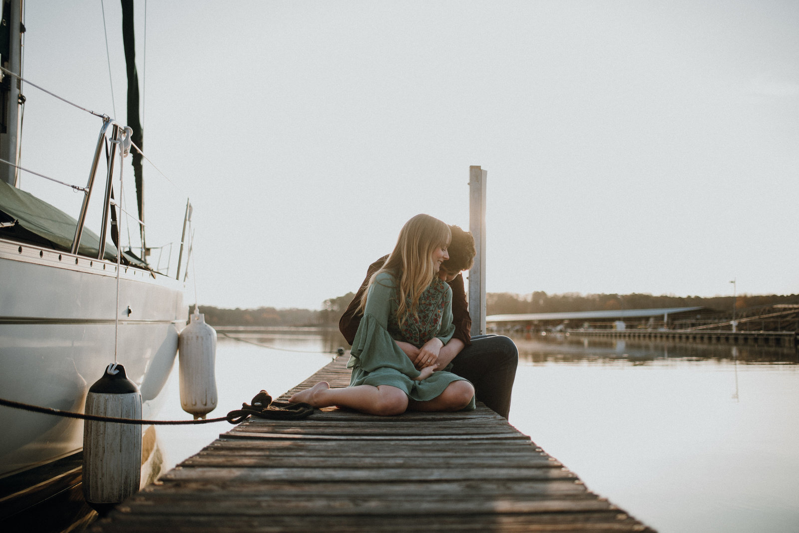 Couple kiss by a sailboat during their Northwest Arkasnas engagement session
