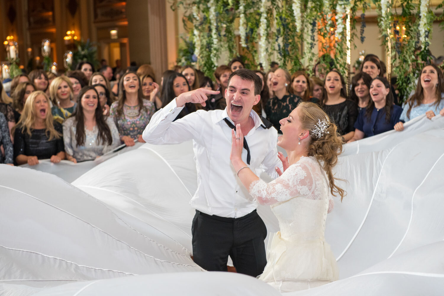 A bride and groom are dancing in front of a crowd of people