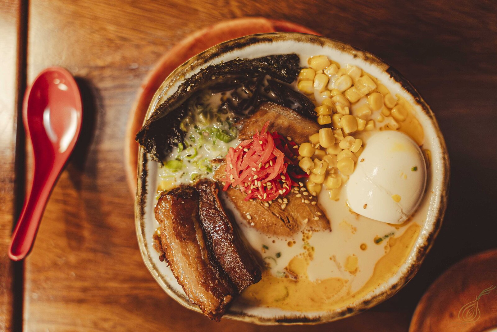 A steaming bowl of ramen adorned with savory meat, sweet corn, and creamy eggs, inviting a delightful dining experience.