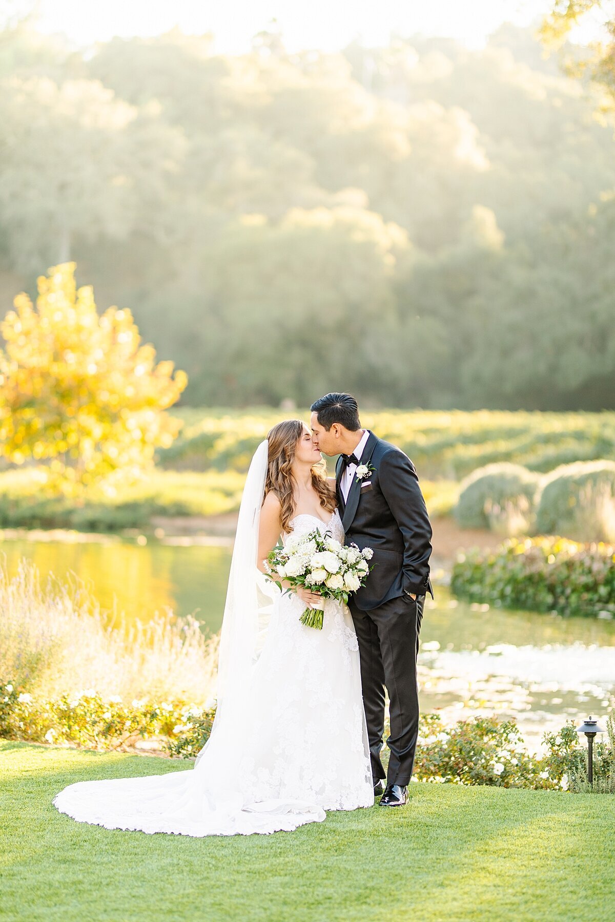 Bride and groom kissing in front of the pond at Monserate Winery Weddings in Fallbrook, California.