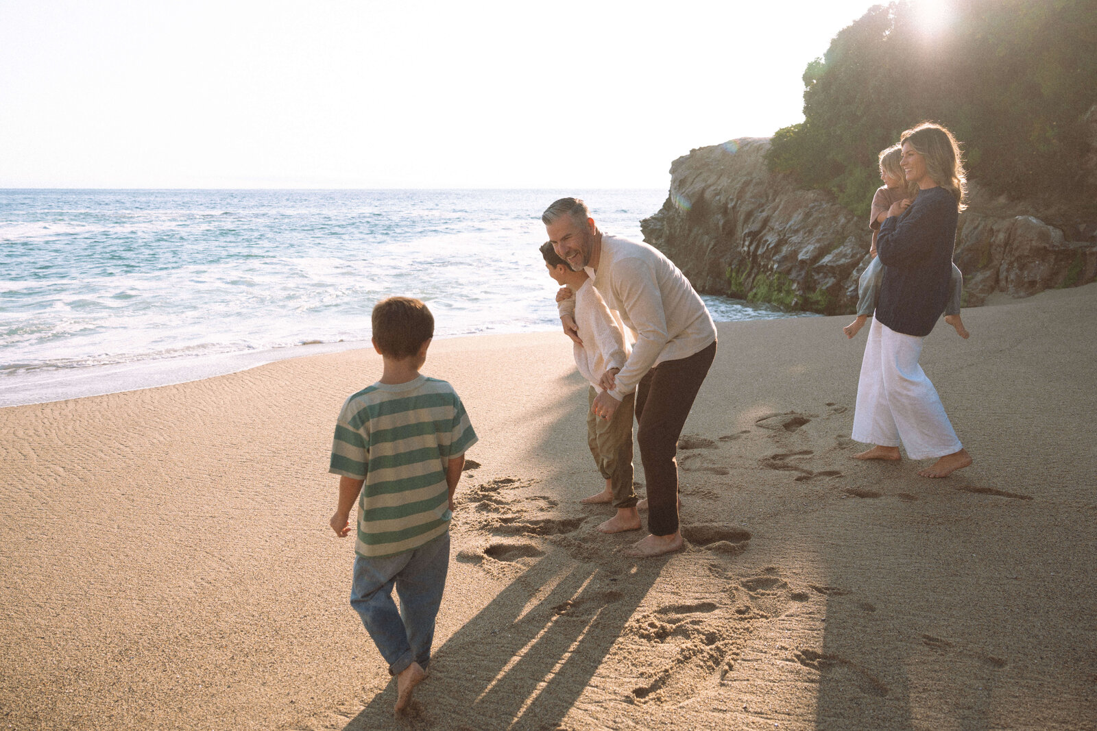Family of five playing near the ocean waves during a relaxed beach photo session in Laguna Beach, California