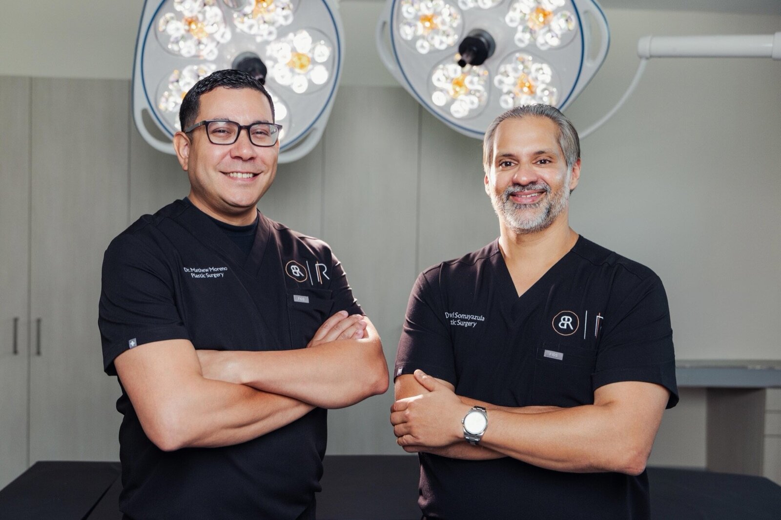 Two Body by Ravi doctors in black scrubs standing under operating room lights