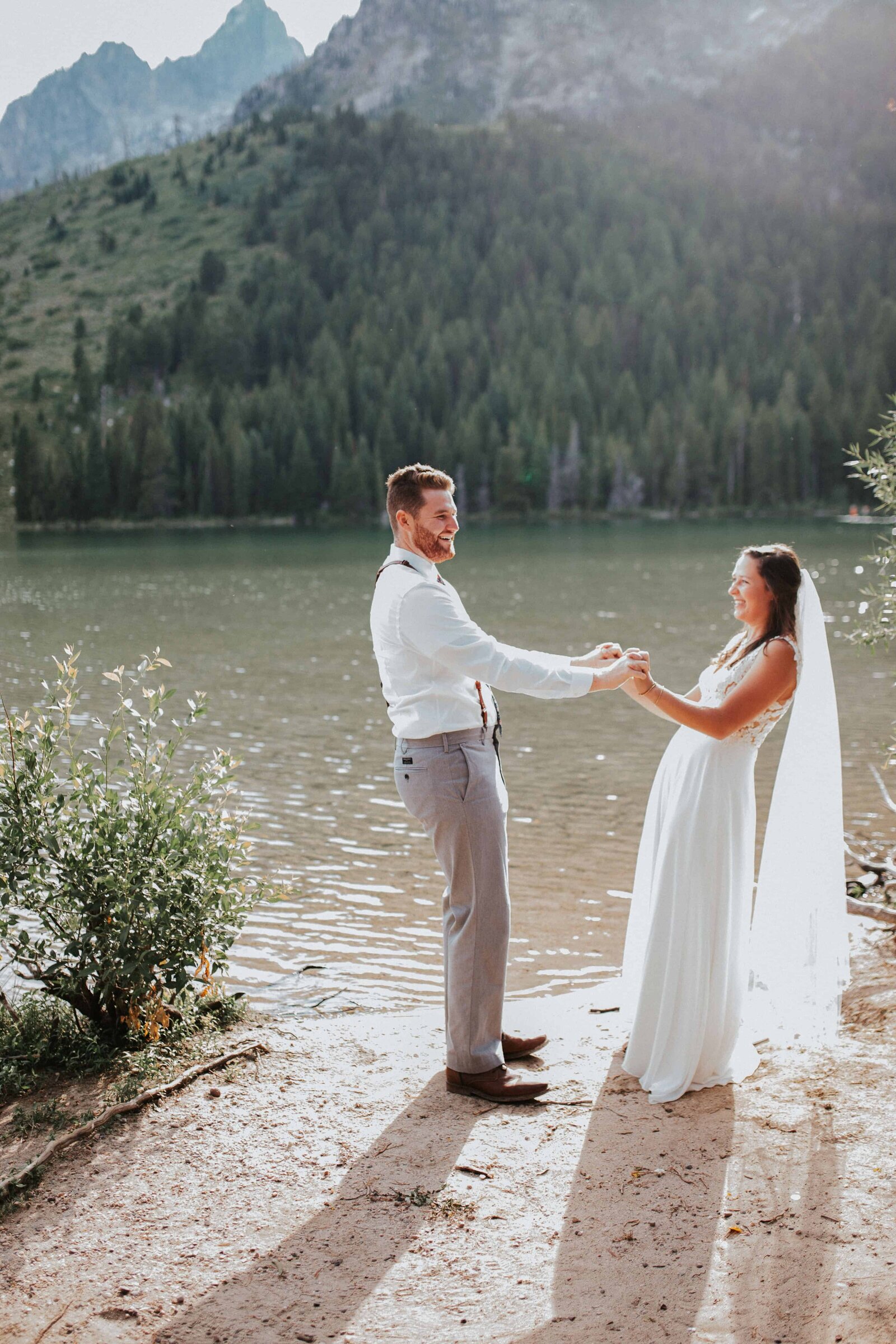 Sacramento Wedding Photographer captures bride and groom playing and holding hands lakeside at Lake Tahoe