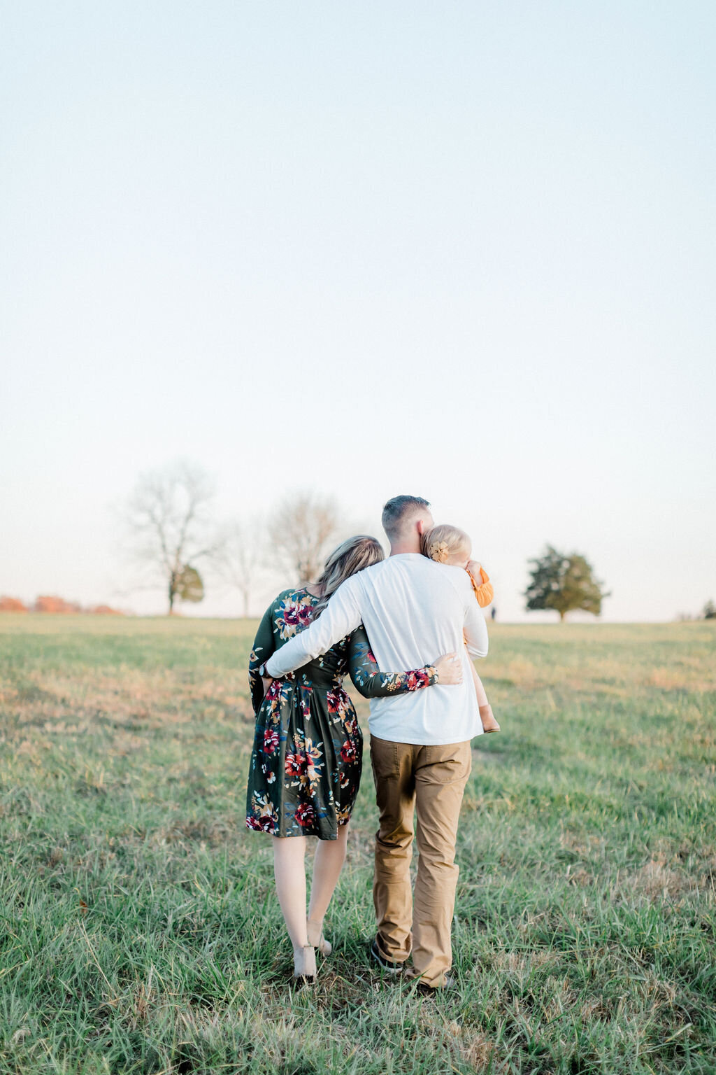 A family slowly walks into the distance holding each other during a family session in Washington, DC at Manassas Battlefield Park.