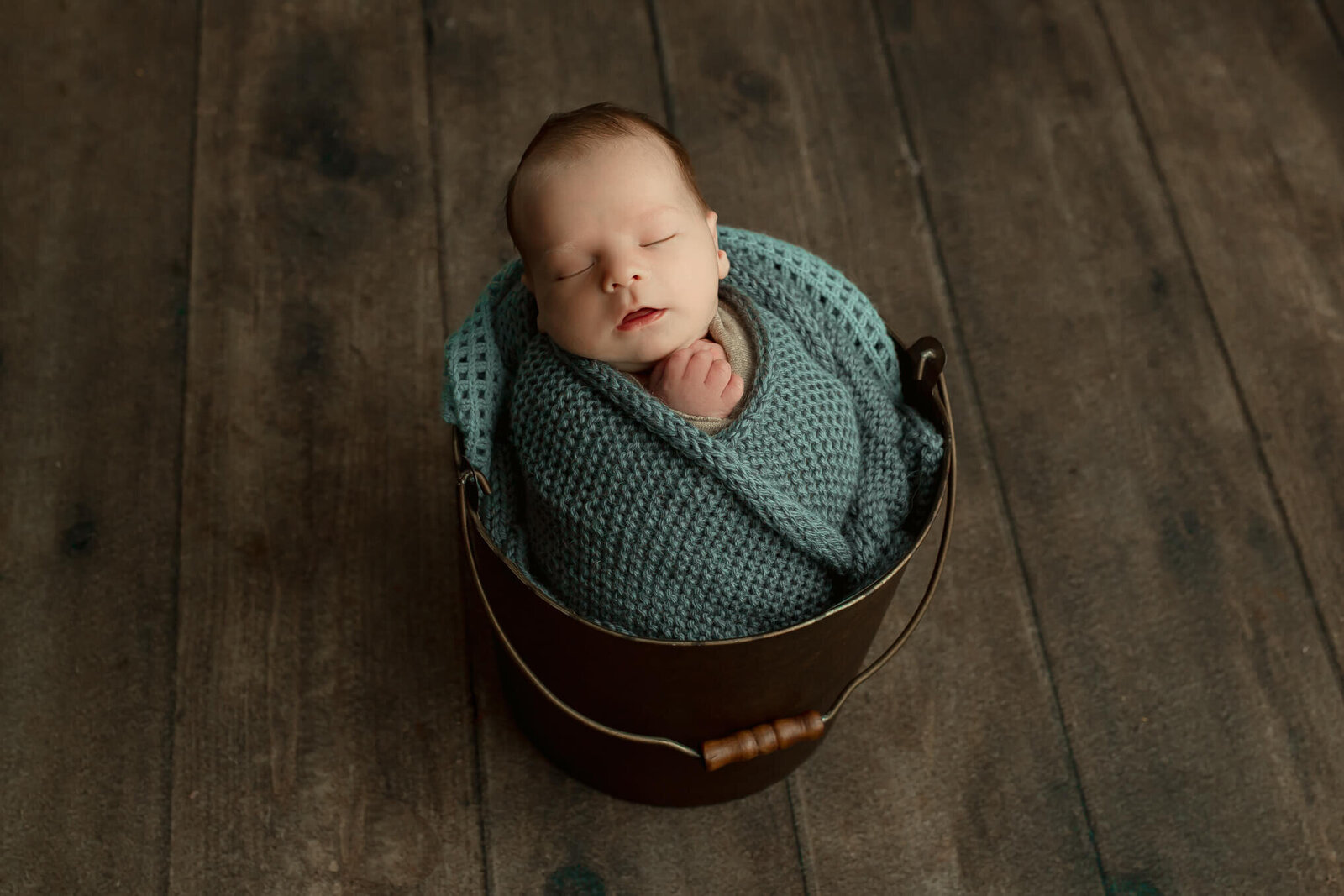 Baby boy swaddled in a blue knit swaddle, sleeping in a bucket during his Harrisburg newborn session