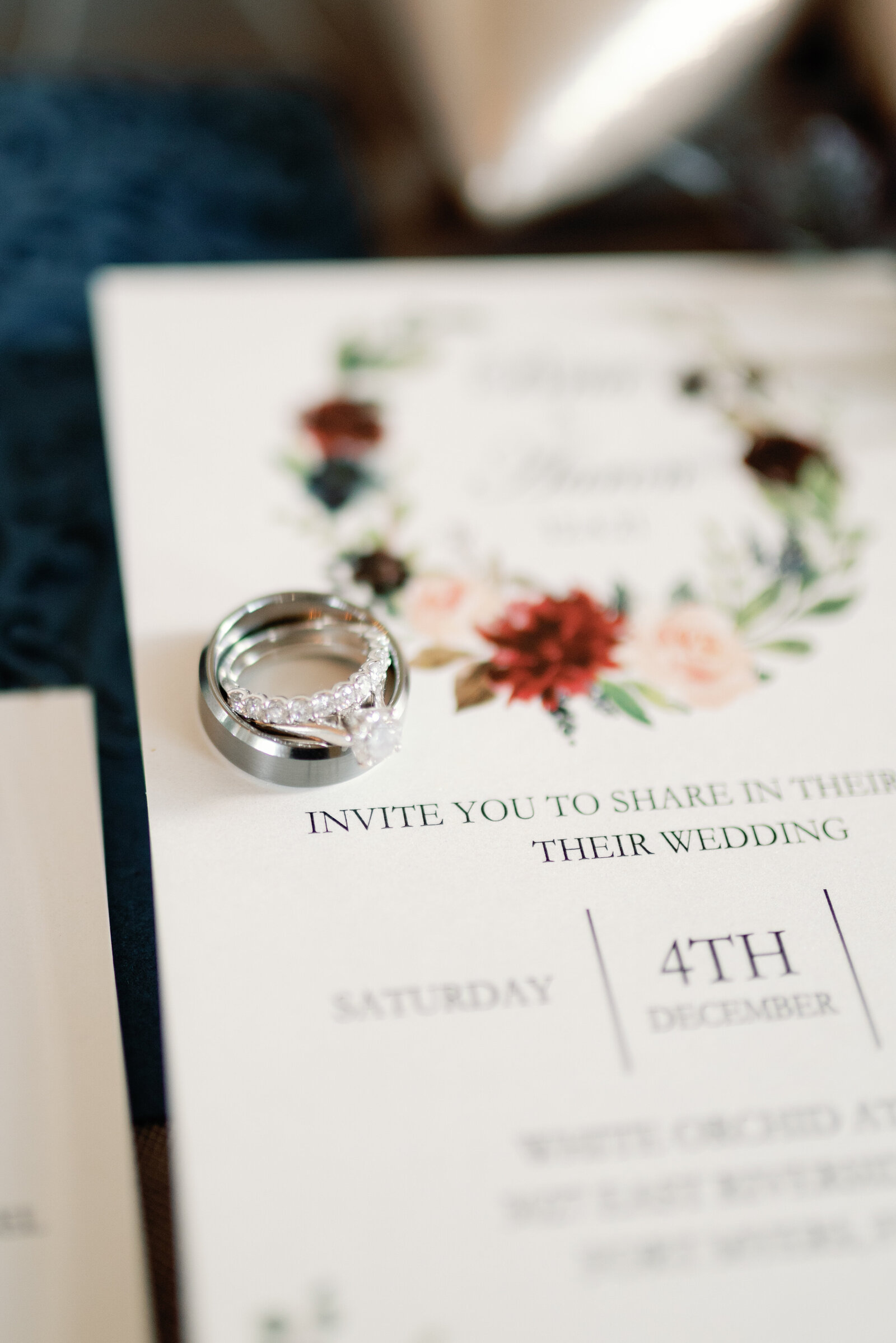 close up detail photograph showing the wedding rings witting on a wedding invitation