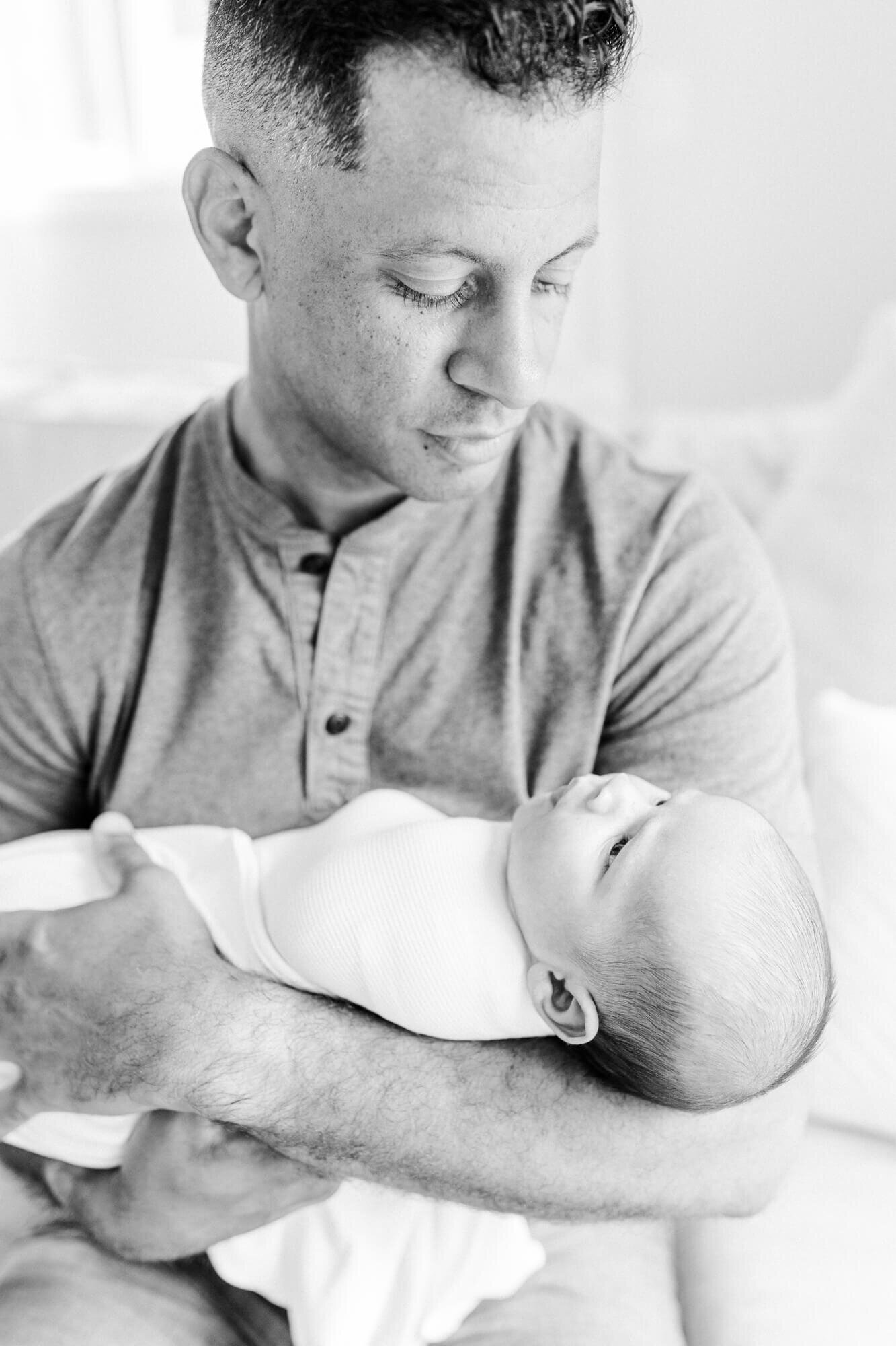 Black and white, dad and newborn look at each other