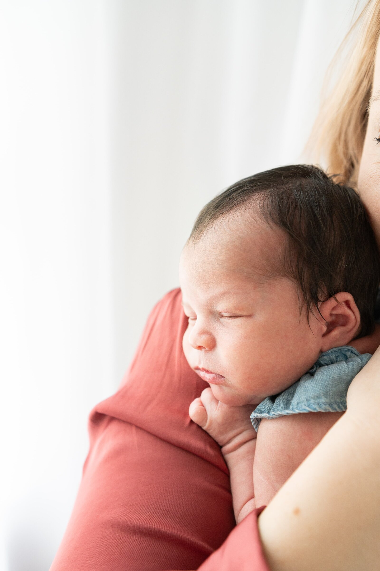 Mother holding newborn close during a lifestyle session full of warmth and love in Baltimore.

