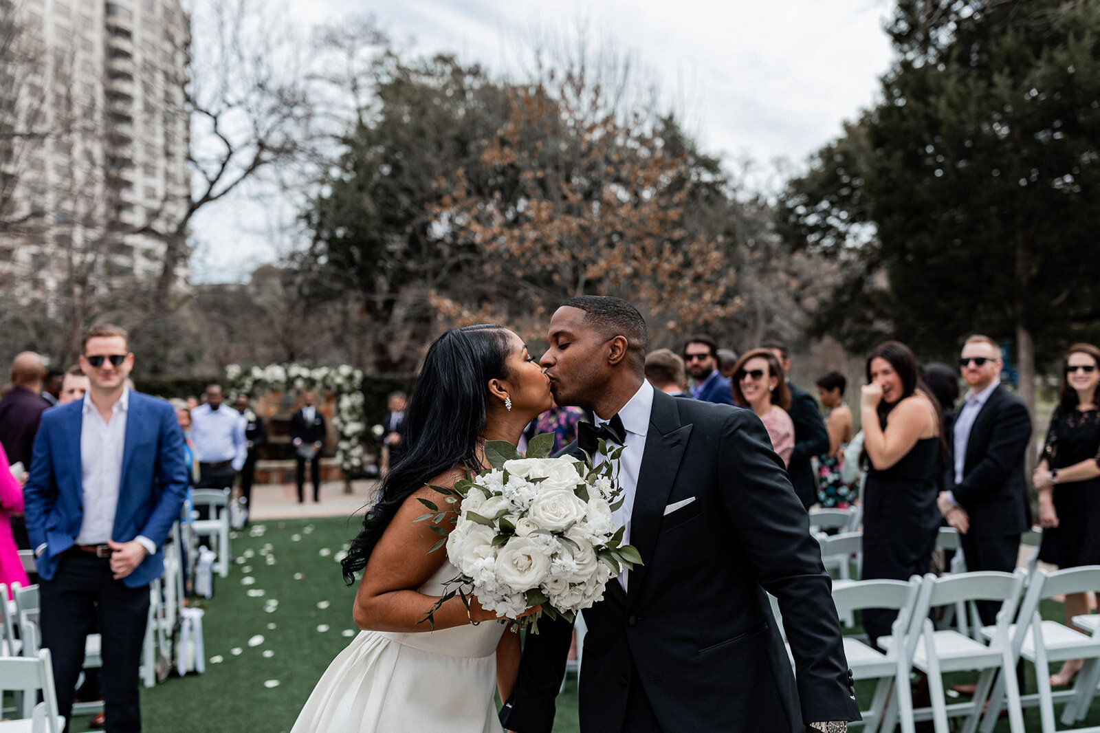 bride and groom kissing and walking down the aisle at an outdoor wedding