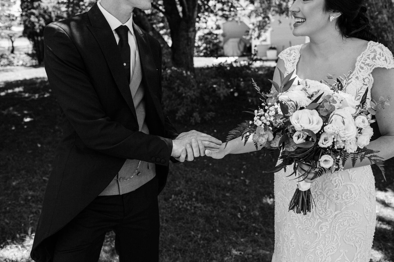 Intimate moment of bride and groom holding hands at outdoor wedding.