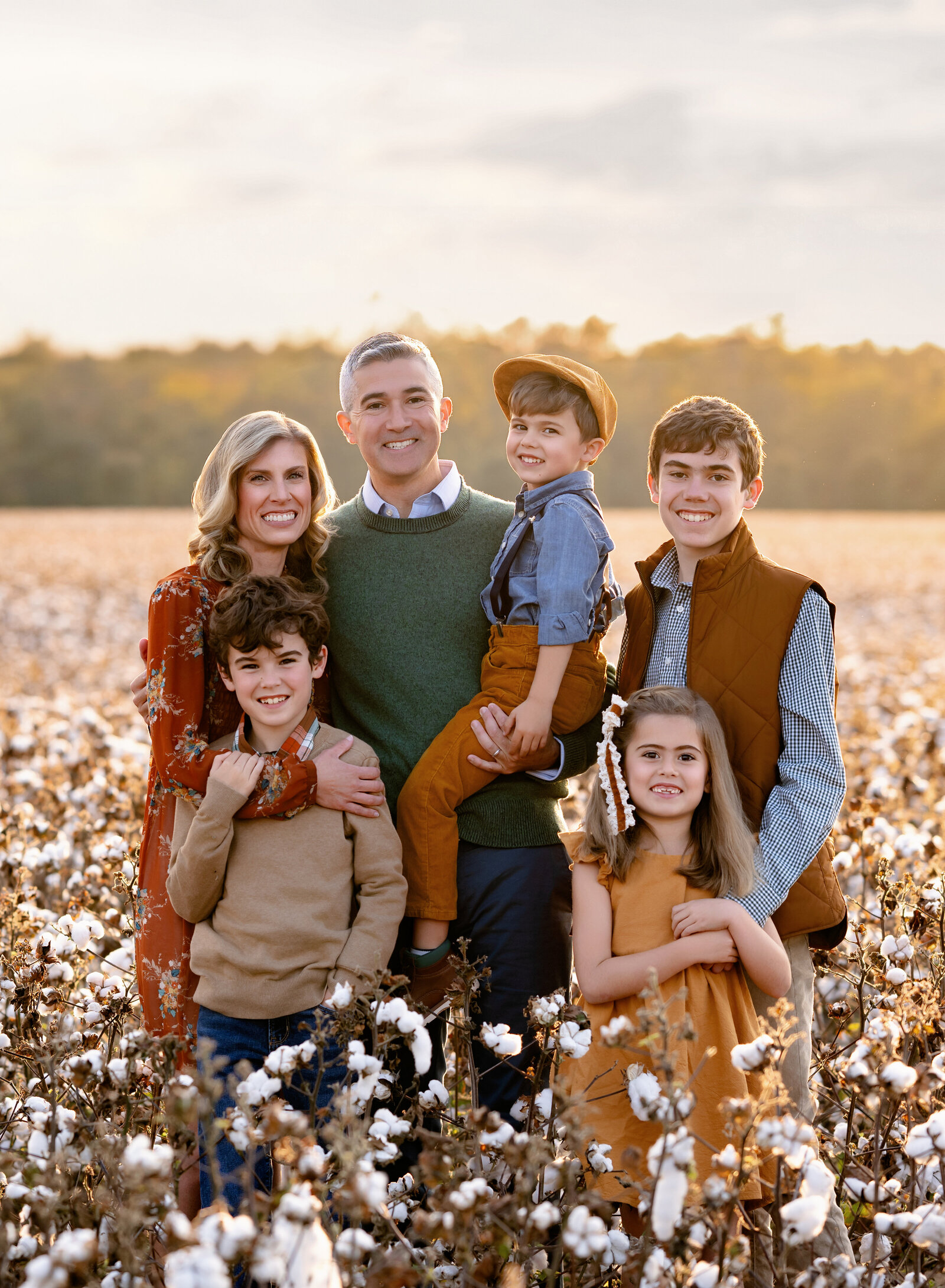 family photoshoot in cotton field with Mom and dad and kids snuggling and smiling. Photo taken in Cartersville GA near Atlanta.