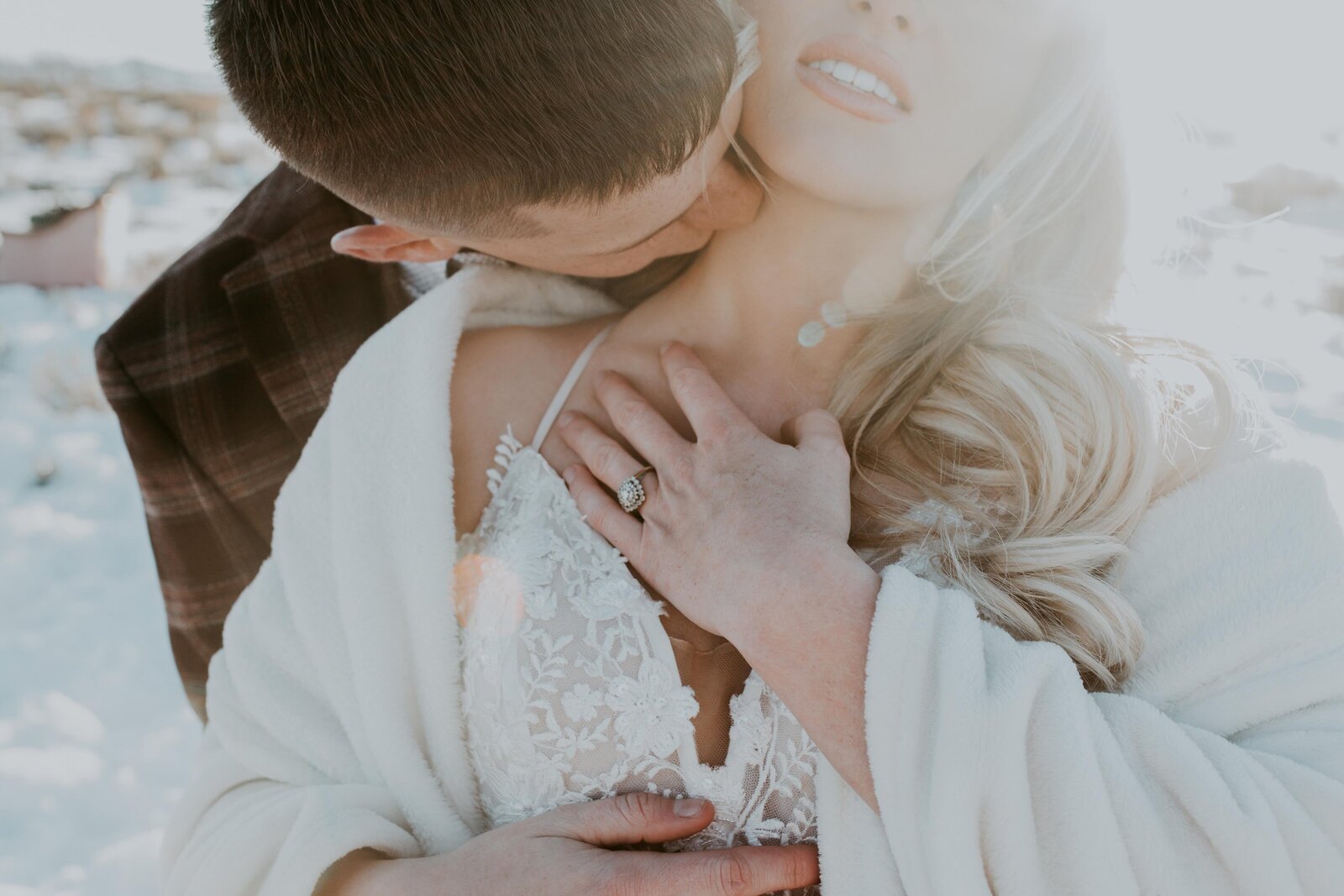 sexy image of groom kissing brides neck as the sun shines from behind them