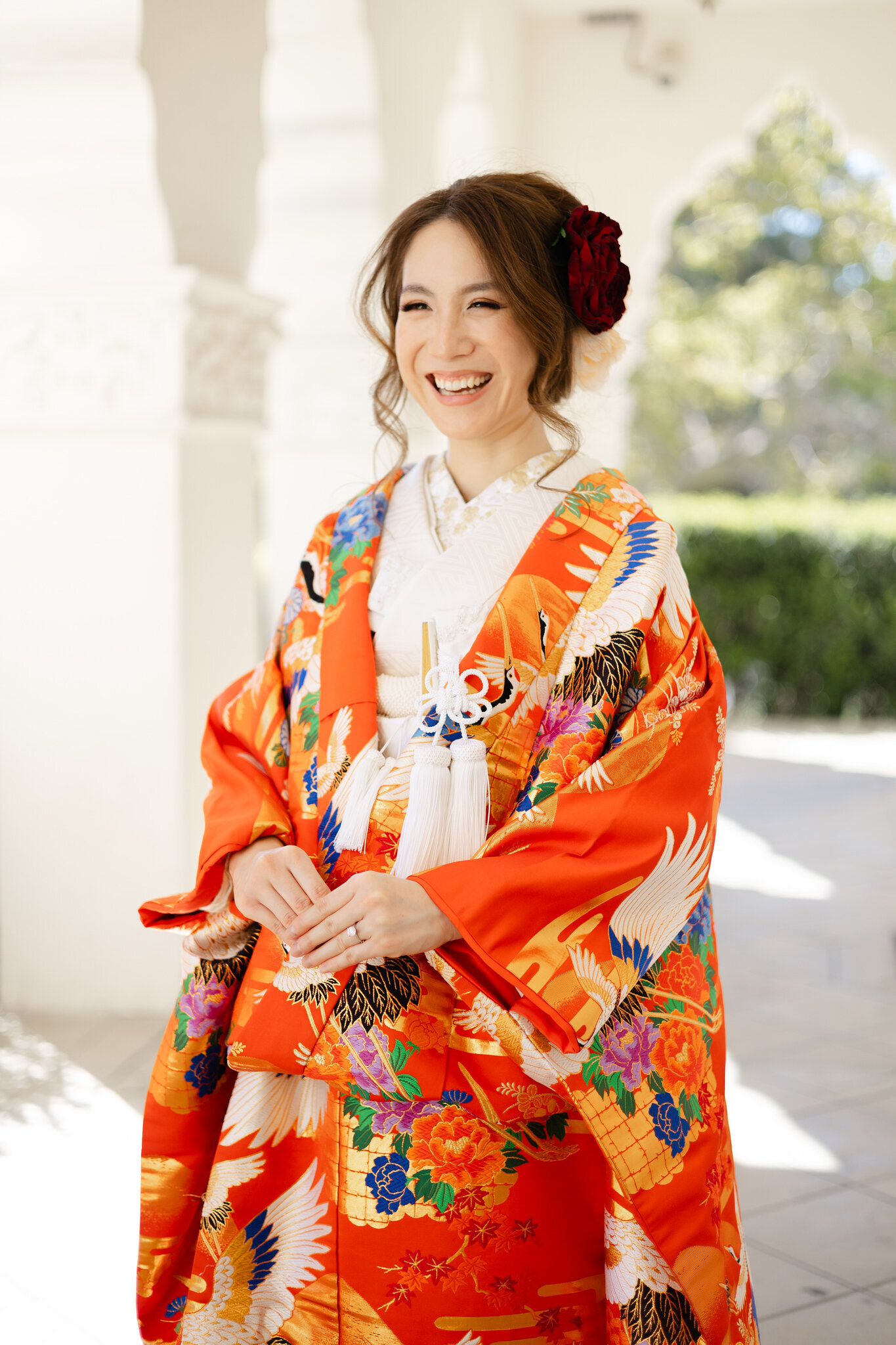 Bride laughing joyfully in bright red iro uchikake with crane designs at Brand Park Glendale, Los Angeles California. Available for wedding kimono rental | 鶴柄の鮮やかな赤い色打掛をまといブランドパーク・グレンデールで笑顔の花嫁。ロサンゼルス カリフォルニアの和装着物レンタル。
