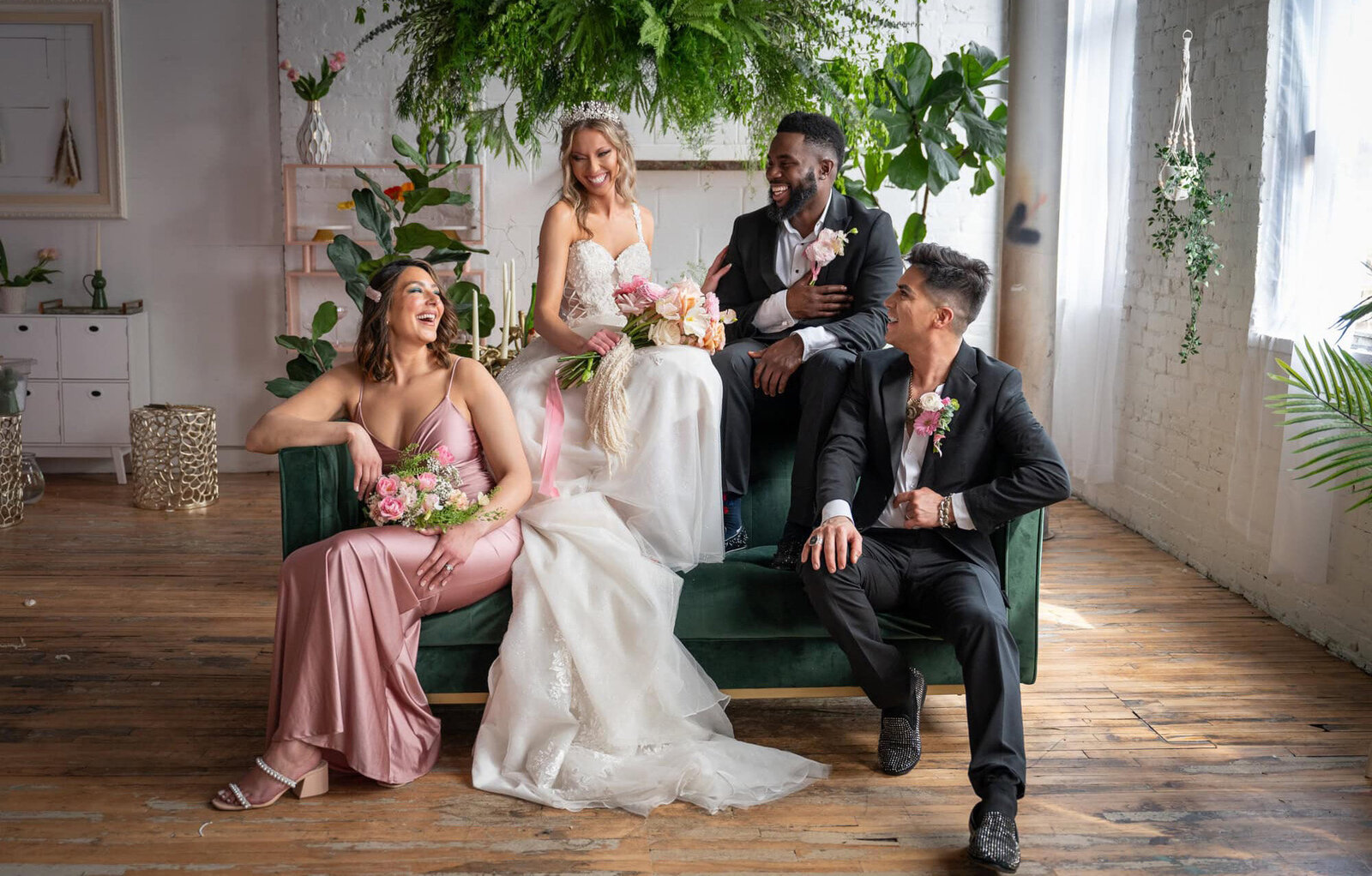 bride and groom with bridesmaid and groomsman laughing together on green couch