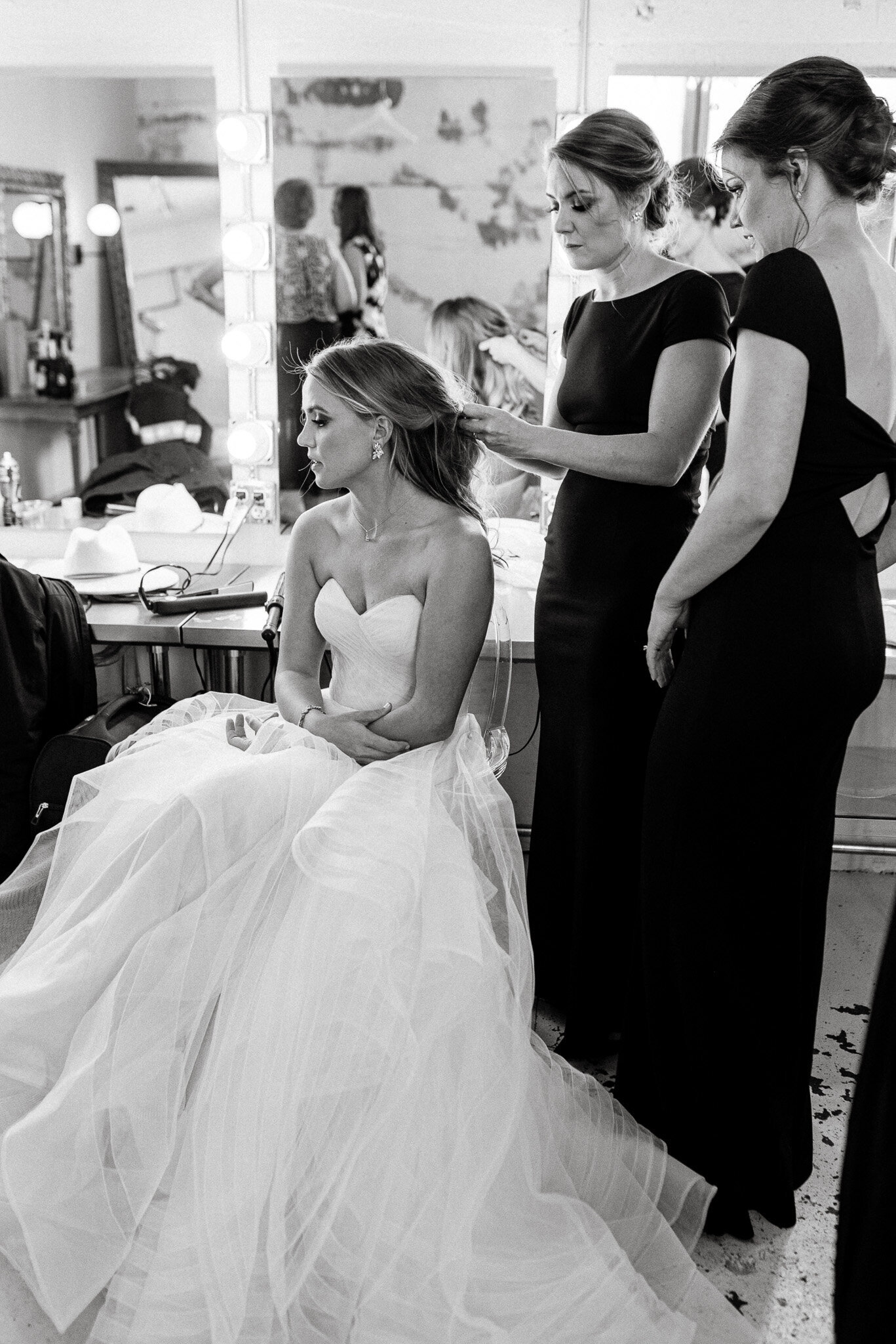 black and white photo of bride getting her hair done by bridesmaid.