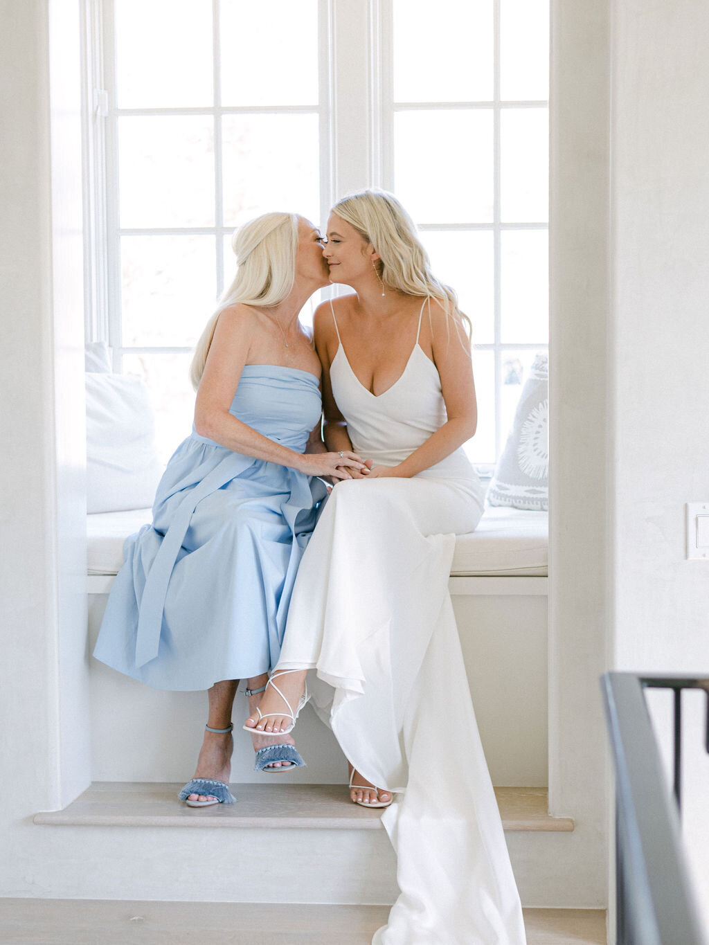 Bride sitting with mother by window at Florida beach wedding