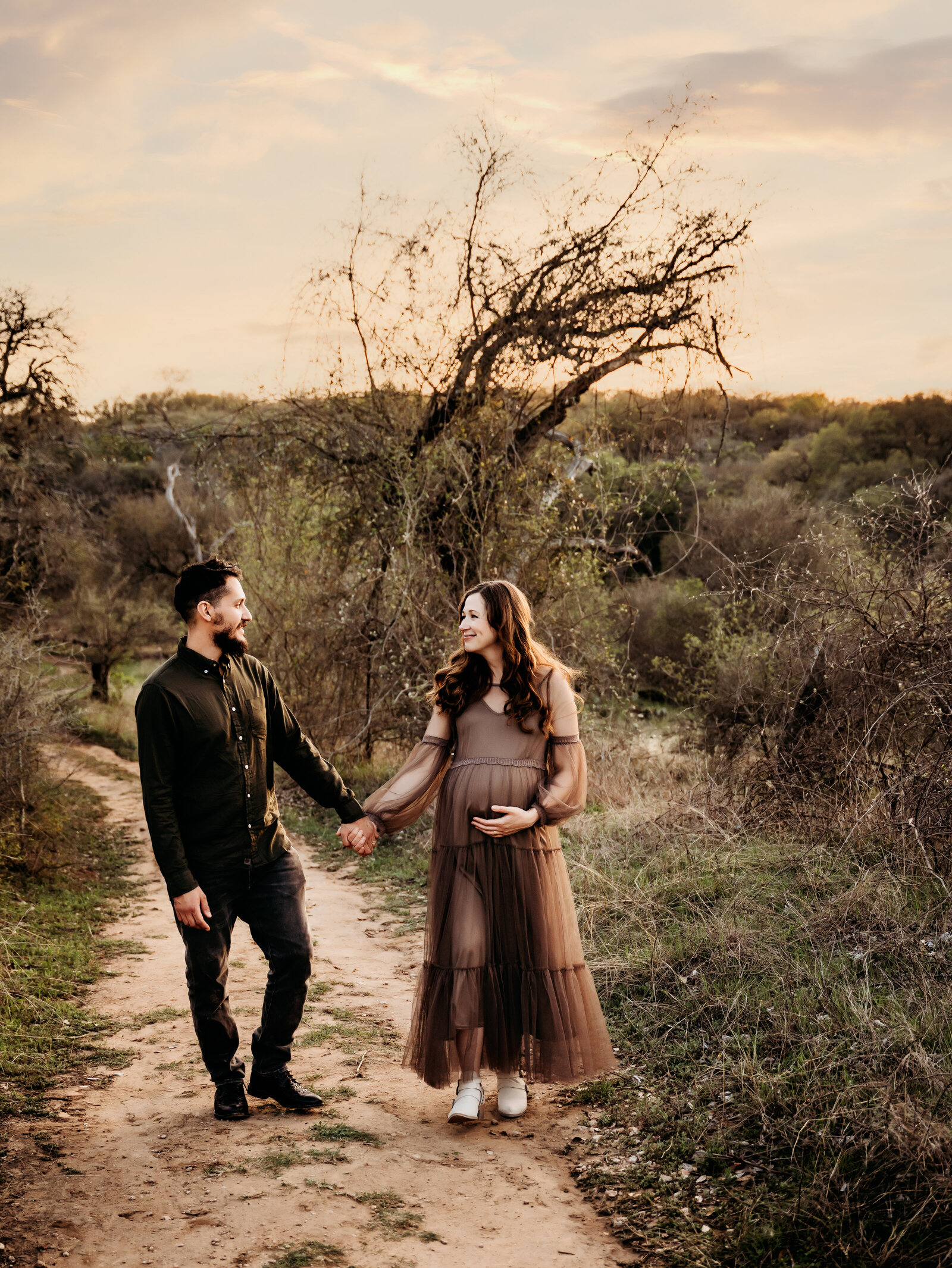 Maternity Photographer, a man and his pregnant wife hold hands as they walk on a country trail