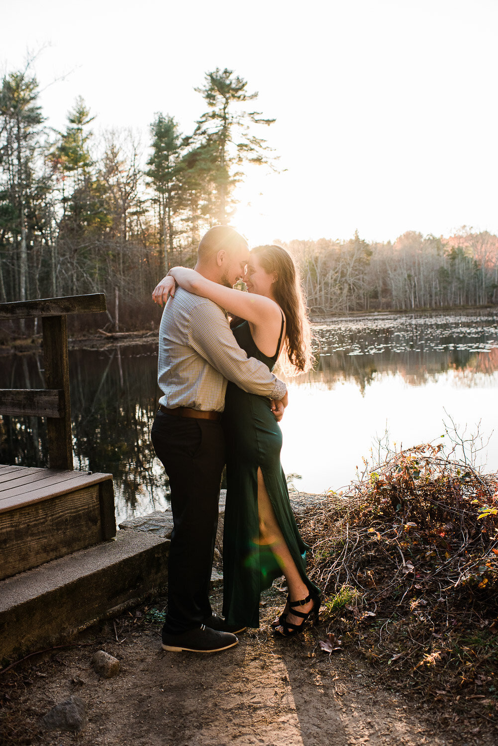 couple hug touch foreheads by water in sunlight