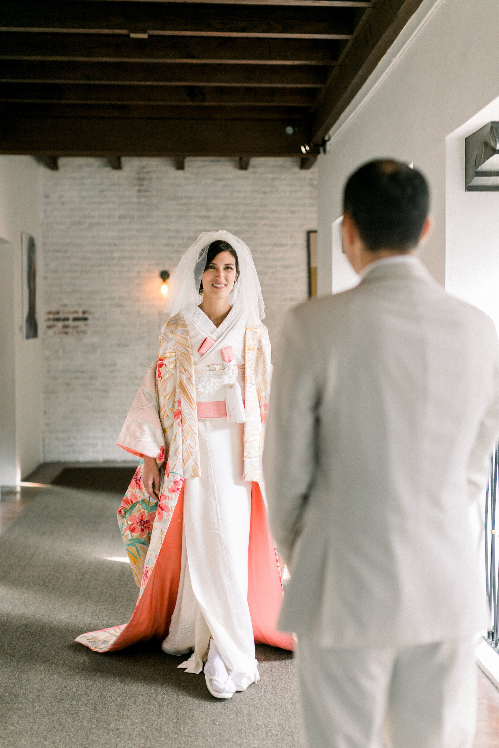 Bride in white wedding kimono with peach and gold details walking toward her groom at The Ebell Club Long Beach, kimono rental Los Angeles wedding photography | ロサンゼルスThe Ebell Club Long Beachで白無垢に金桃色の打掛を羽織り新郎へ歩み寄る花嫁、着物レンタルウェディングフォト