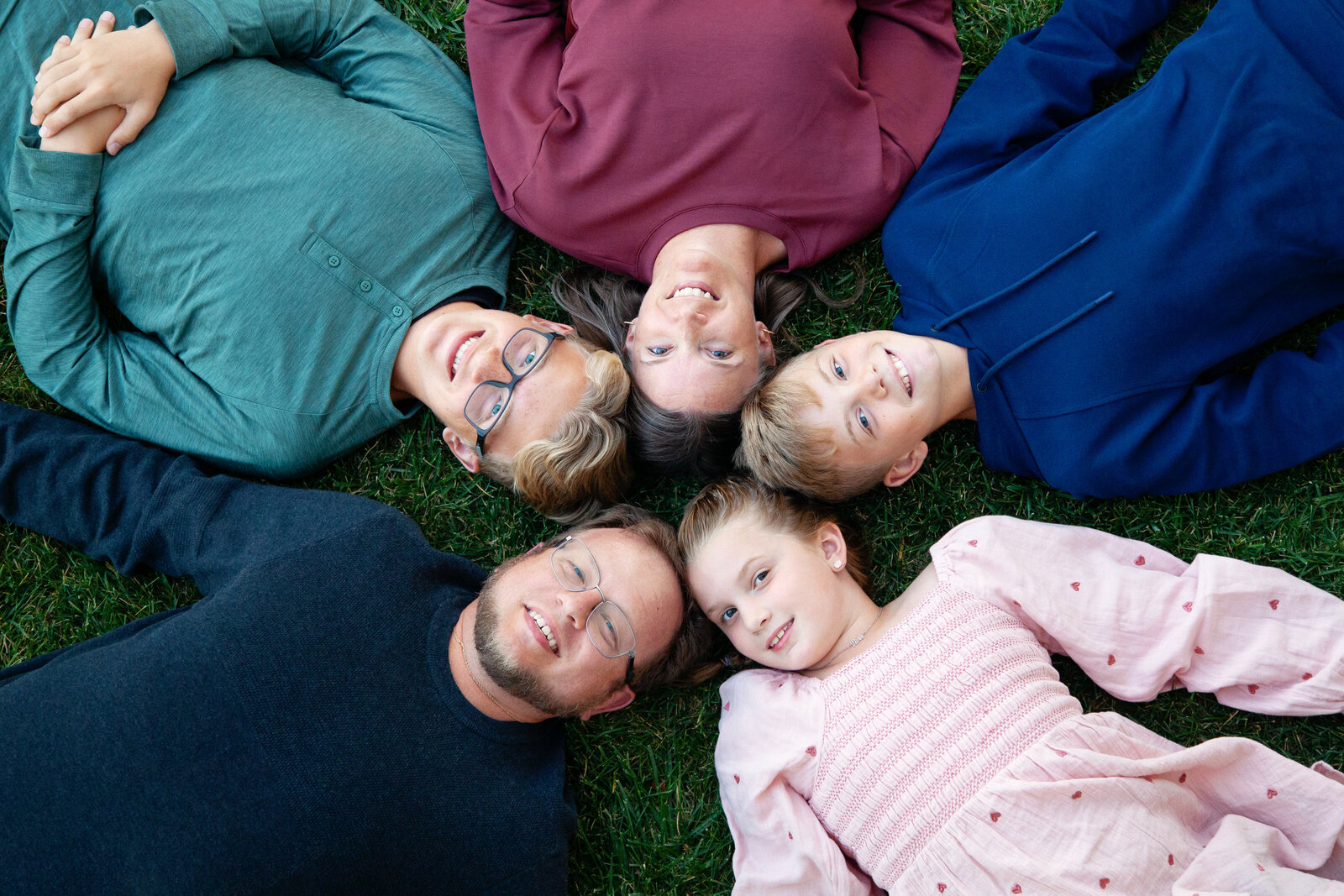 Family of five lying down on backs in a circle, shot from above.