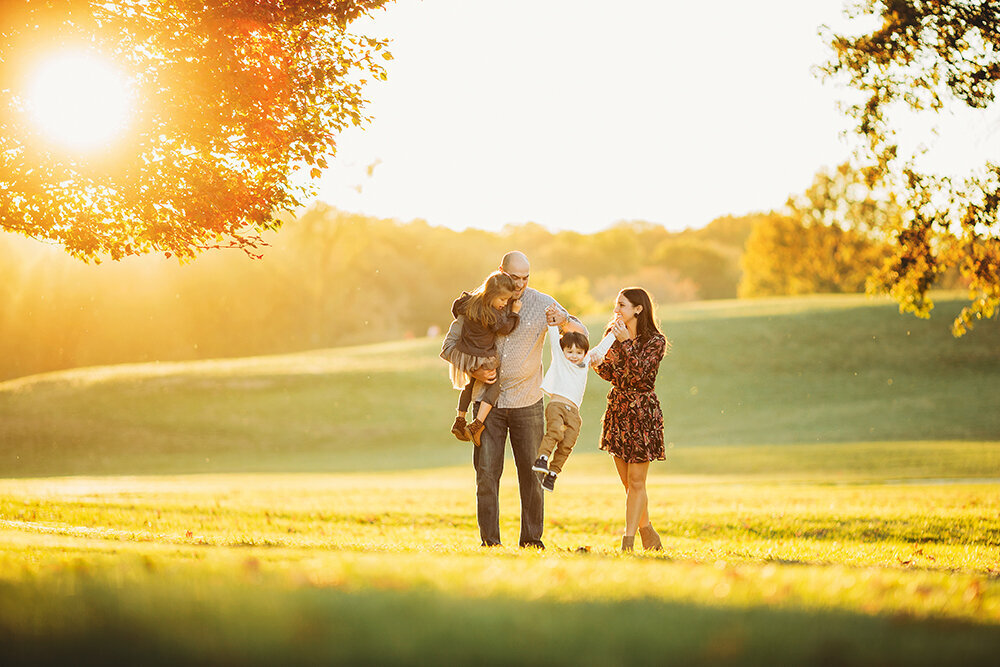 Family photography, family posing in field with sun setting in the background