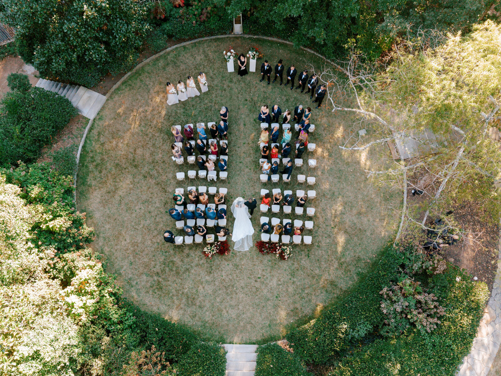drone photo from above birds eye view of bride walking down the aisle into the garden ceremony 