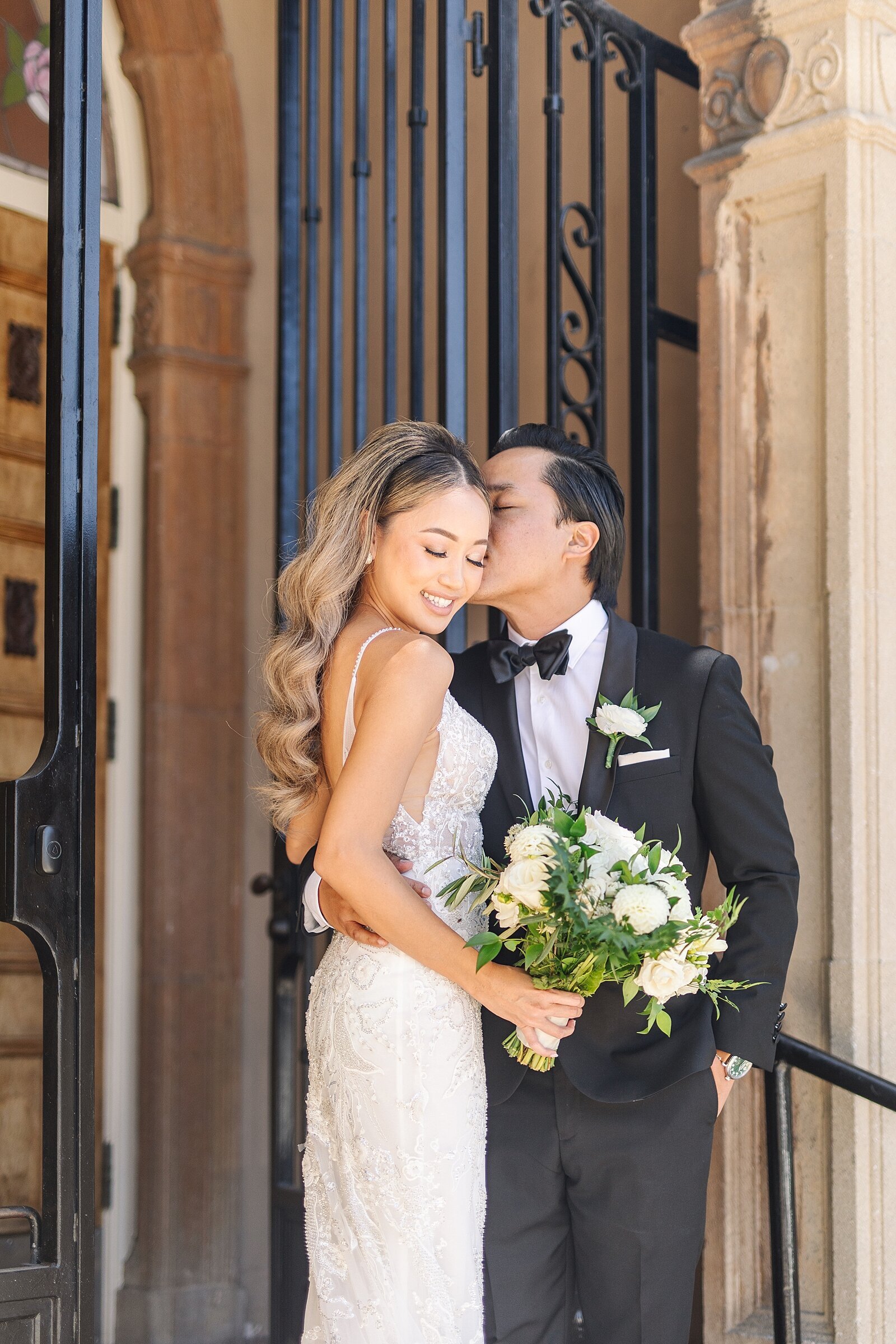 Bride and groom kissing outside doors of the Ebell of Long Beach by wedding videographer, Sherr Weddings, based in Newport Beach.