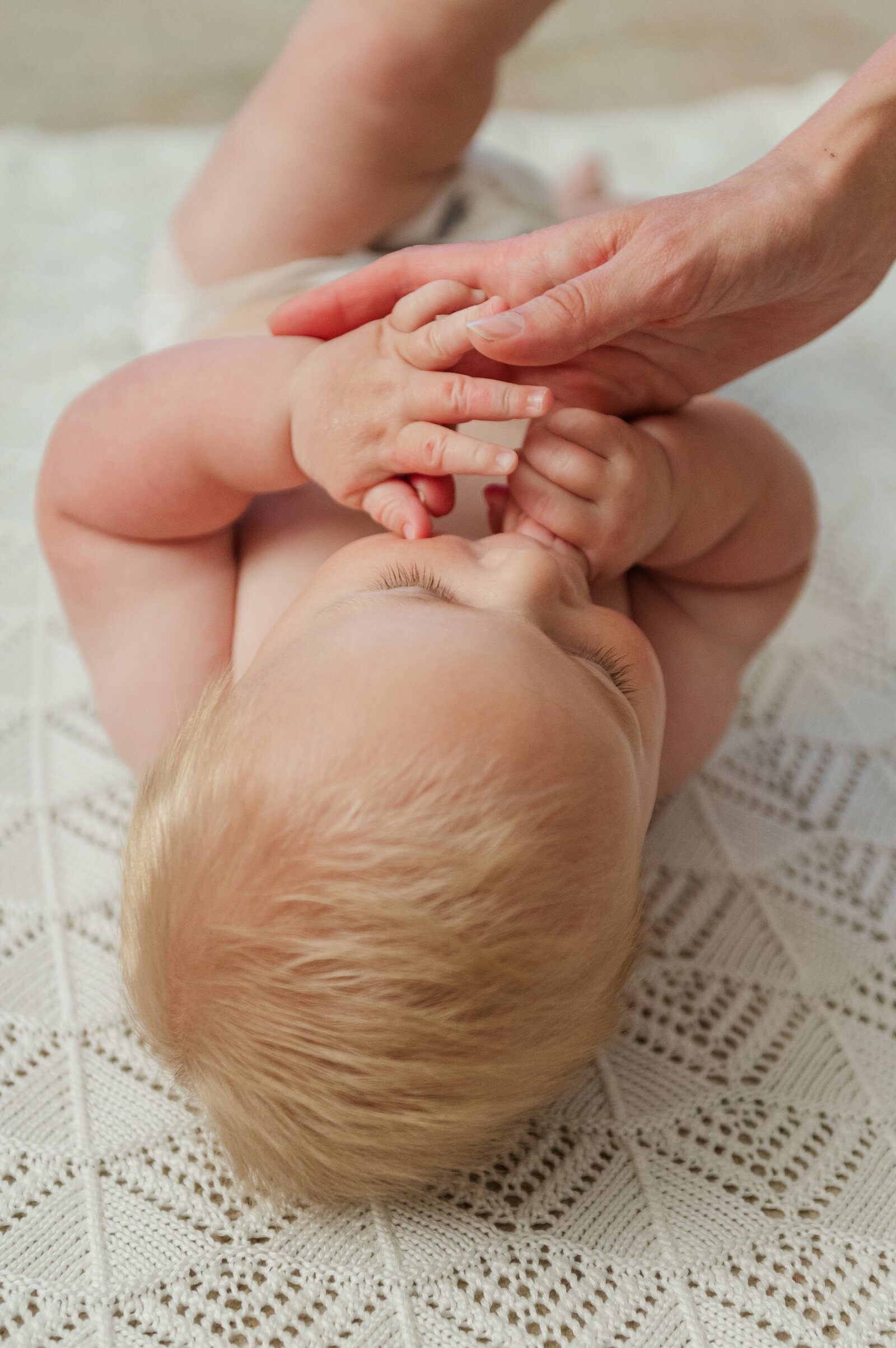 Baby laying on his back while sucking on moms fingers by lancaster pa photographer