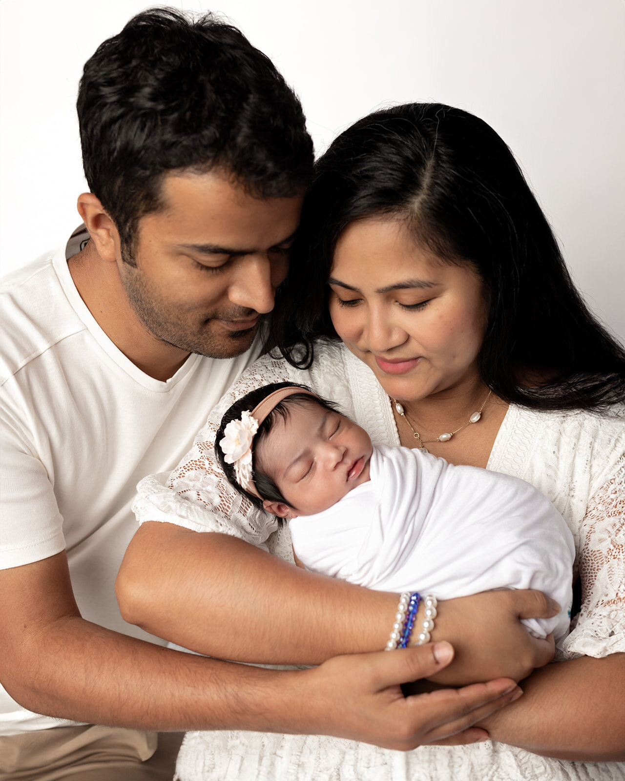 mom and dad holding newborn baby girl for studio portraits