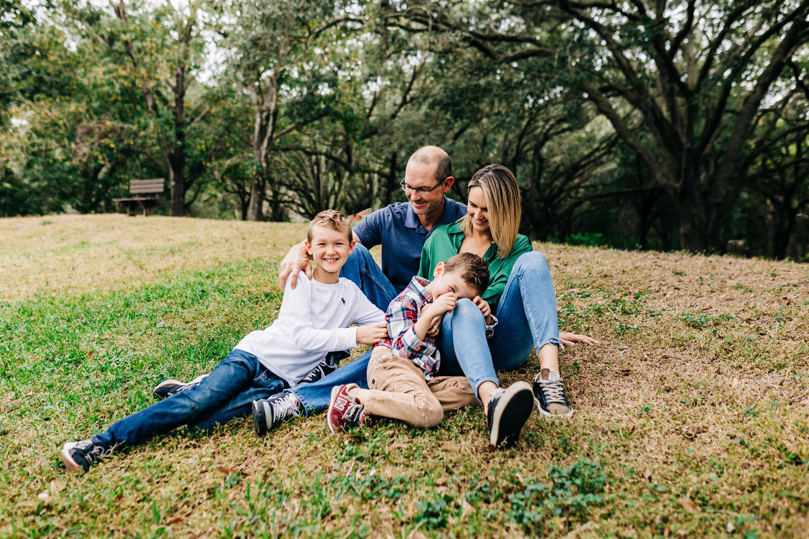 family with two older boys cuddling in a park near st. pete