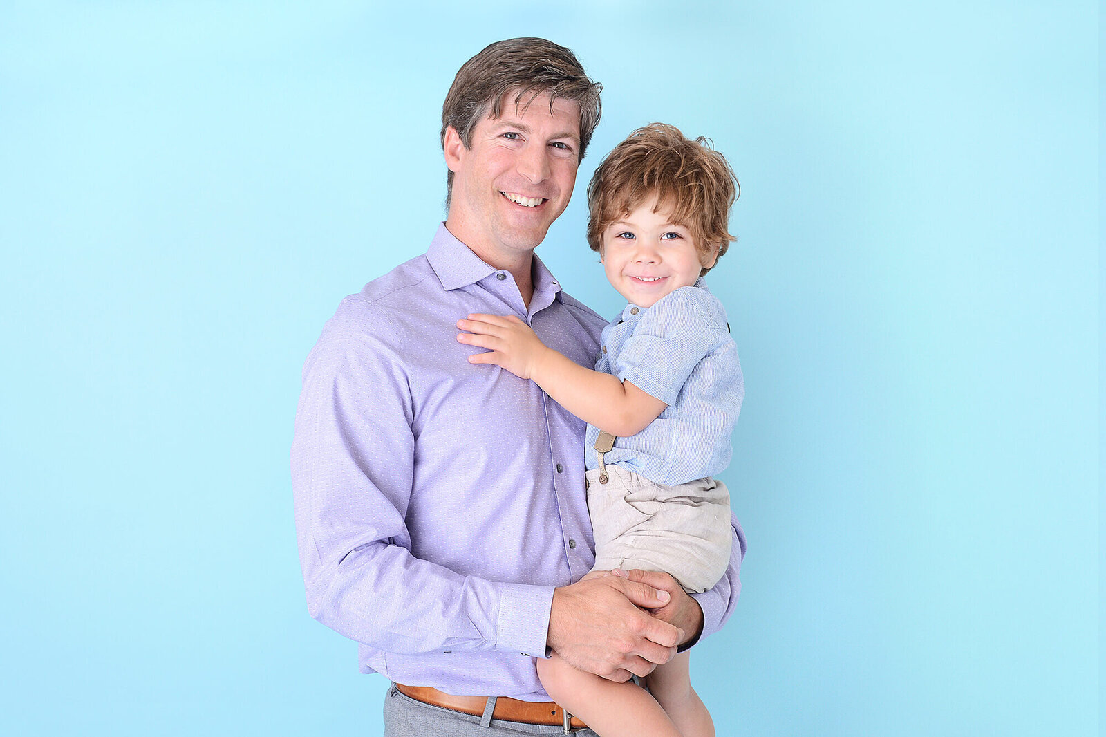 dad and son smile at the camera at their photoshoot in houston