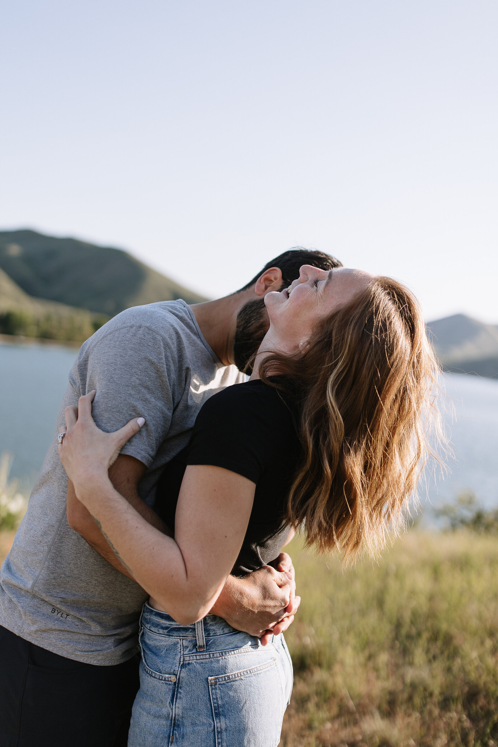Candid couple hugging and laughing in natural light at Boise’s Lucky Peak Lake