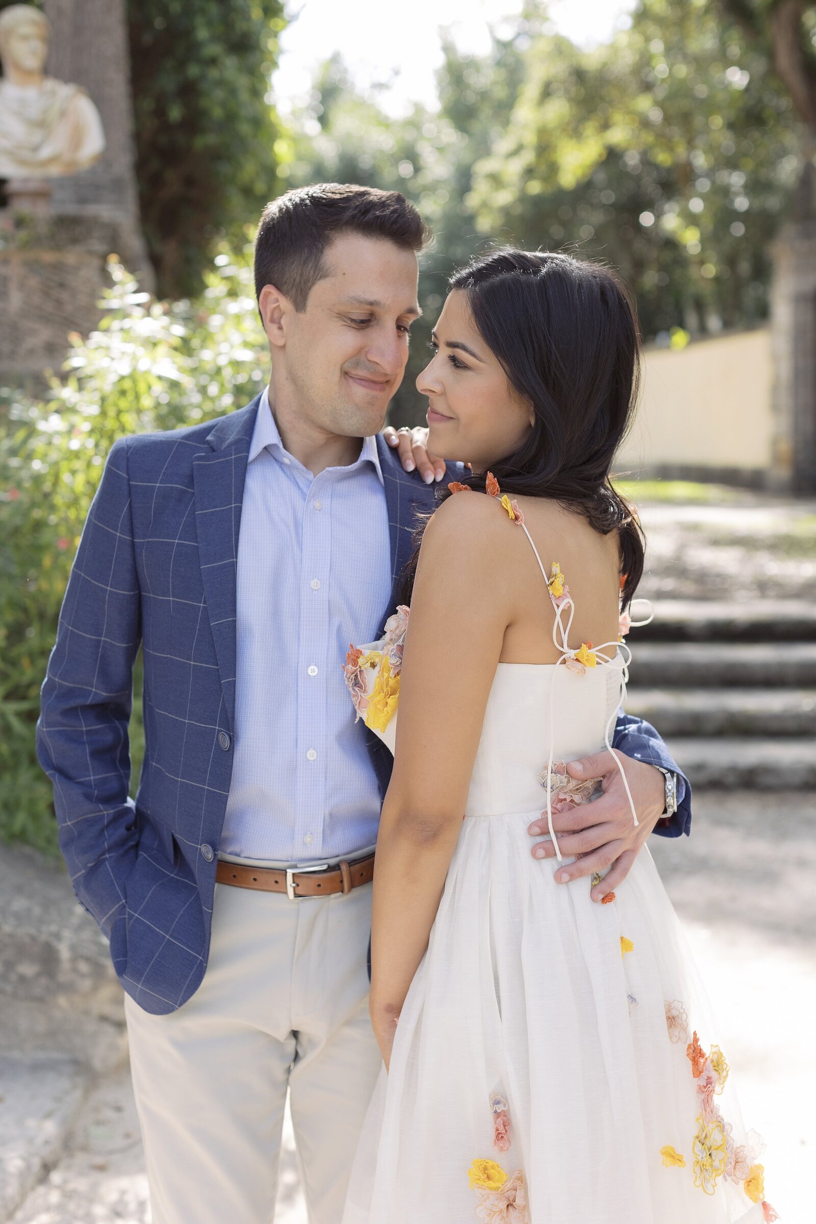 Man in navy suit jacket holds a women in a floral dress while at Vizcaya, Miami.