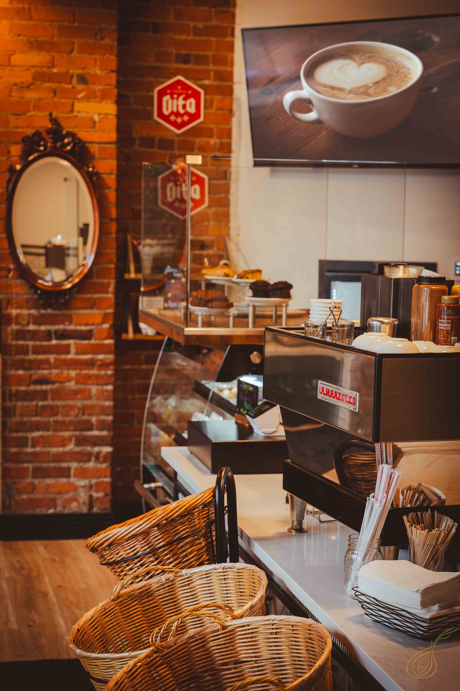 A cozy coffee shop featuring a rustic brick wall and a sleek coffee machine, inviting patrons to enjoy their beverages.