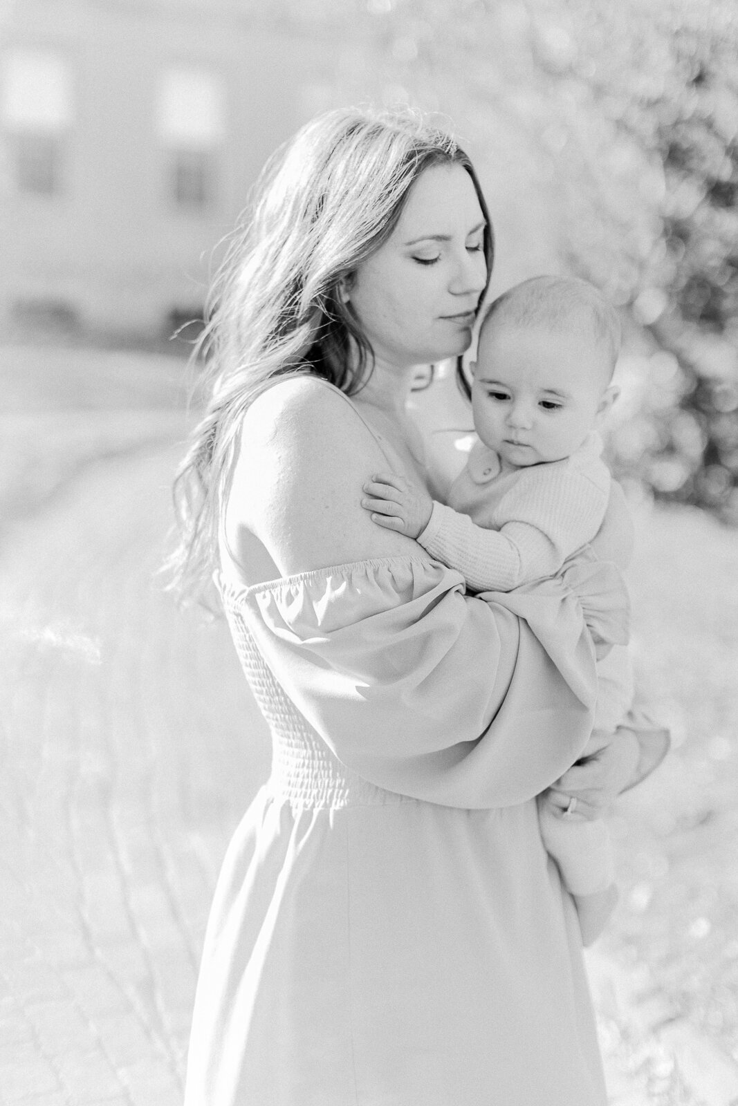A black and white image of a mother holding her baby boy and closing her eyes and savoring the moment with Boston family photographer Corinne Isabelle