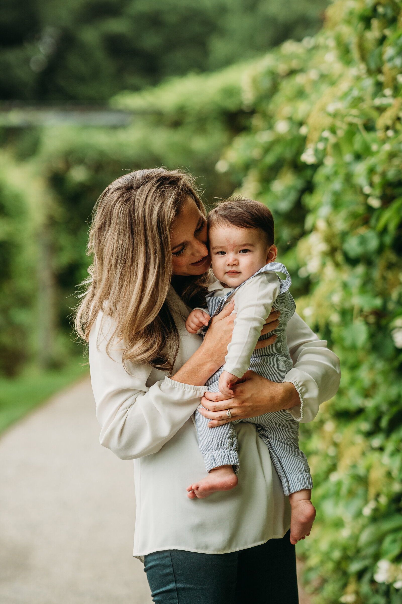 mother holds baby boy close in front of ivy wall in JP