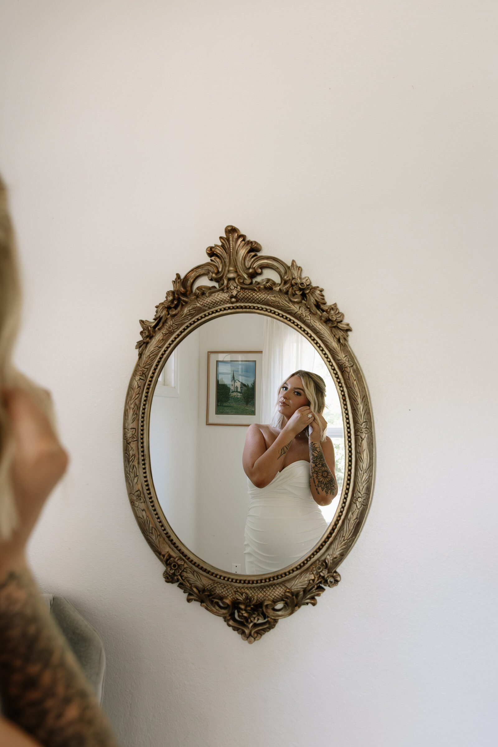 Bride putting on her earrings in mirror ahead of Boise wedding ceremony