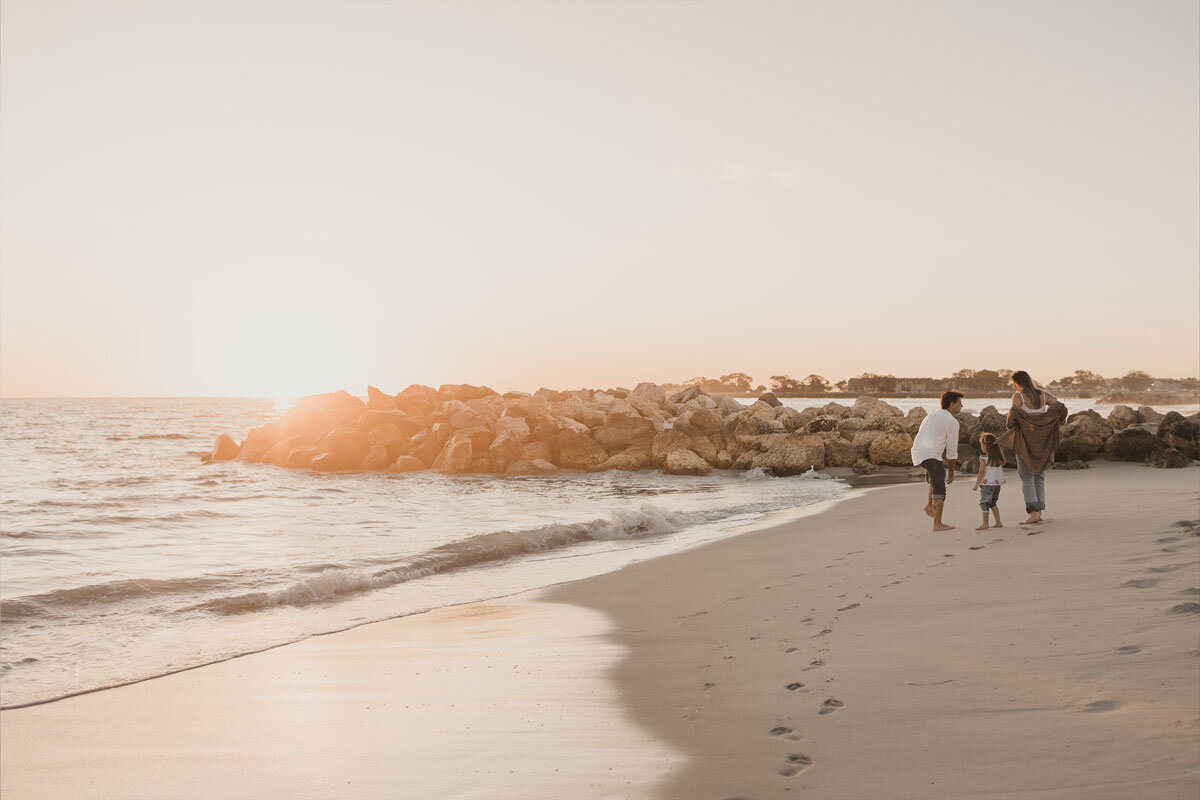 A family on the beach at sunset. The mother is 8 months pregnant.