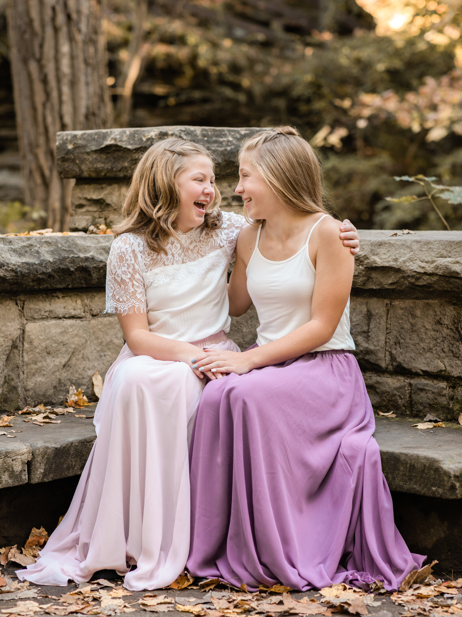 two sisters sitting on rock bench for family photos