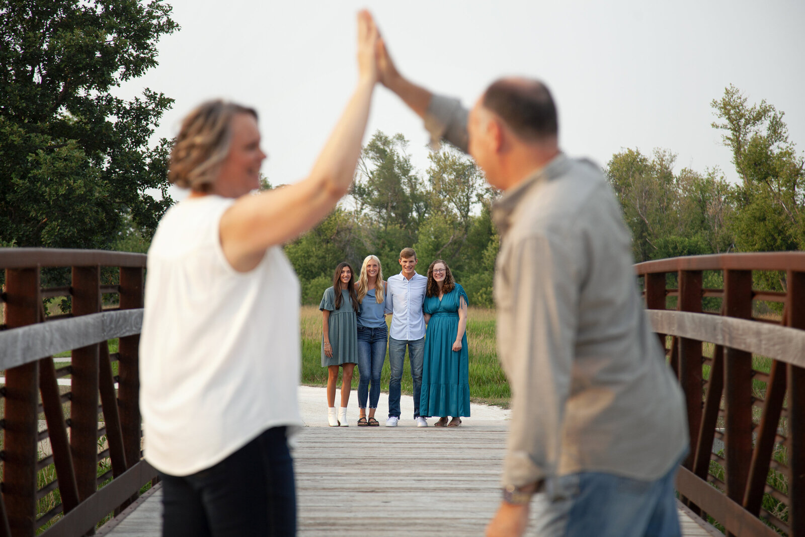 Parents high five out of focus in foreground with four grown children in focus under their high-five.