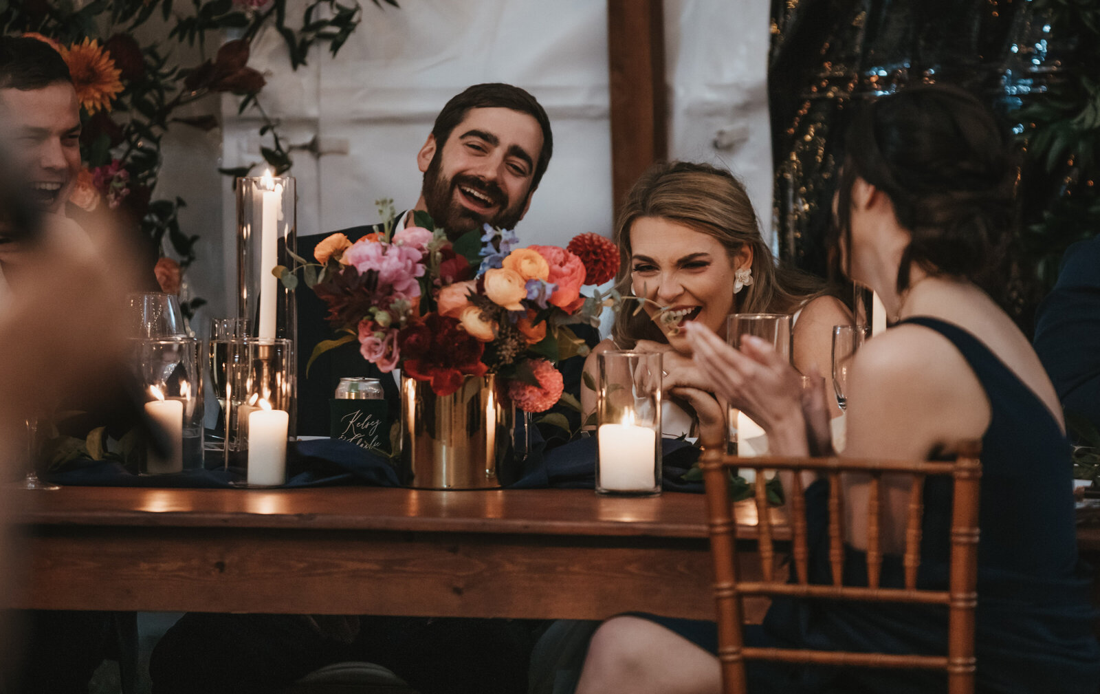 A bride and groom laugh during toasts at their wedding