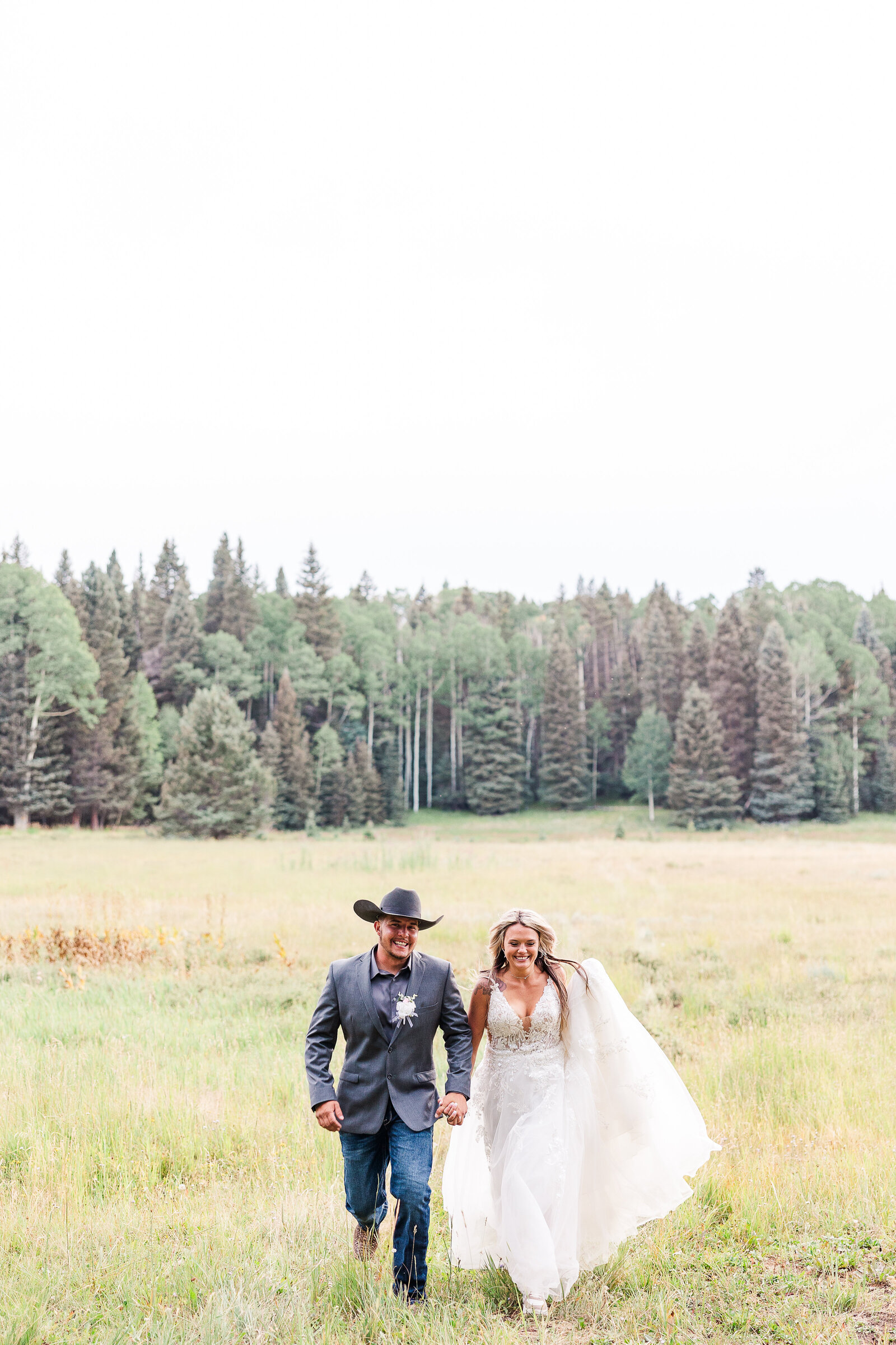 Fun image of bride and groom running up the field together in Arrowhead Colorado